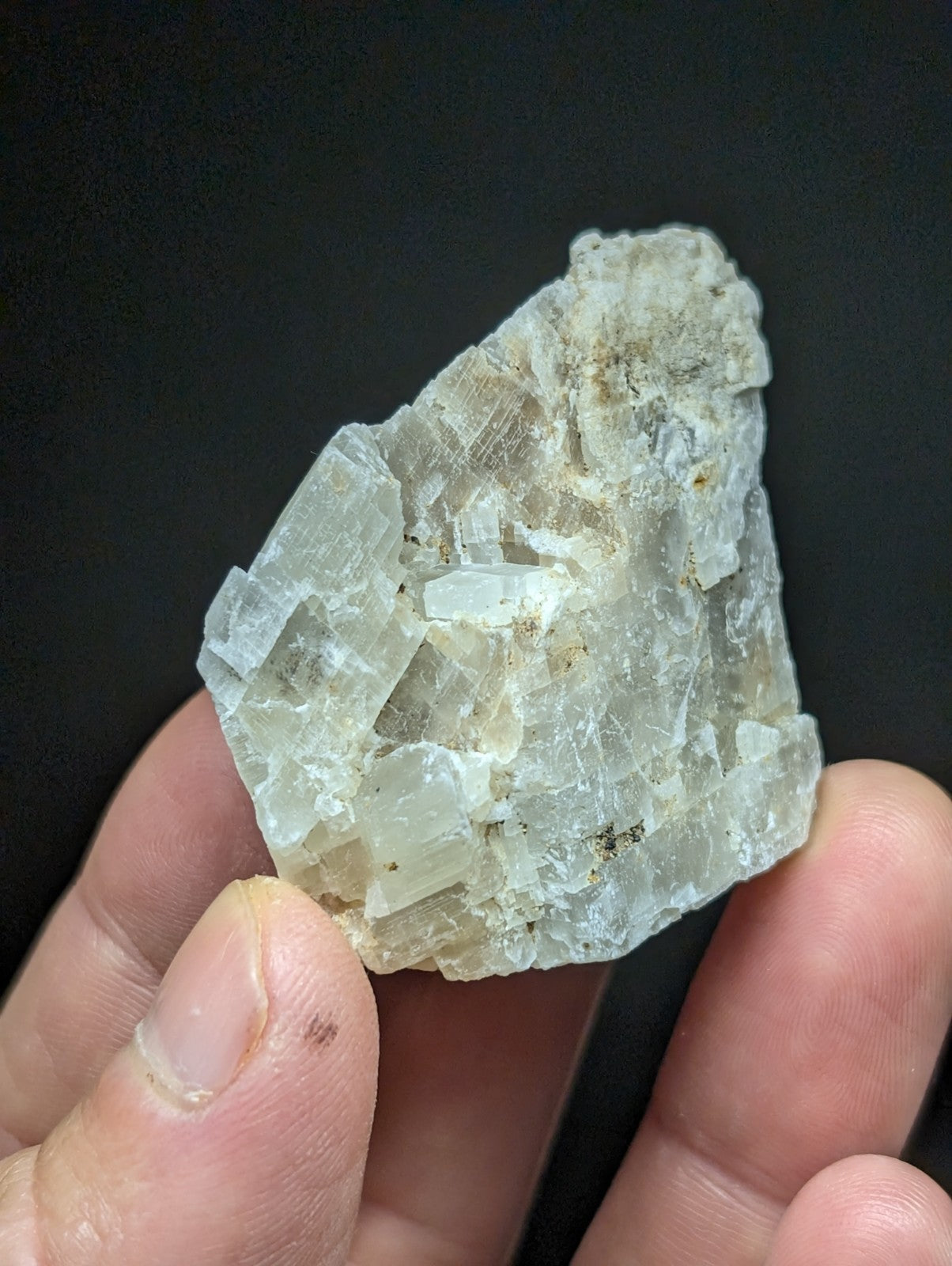 A translucent, pale greenish-white mineral specimen with visible crystalline facets and a rough, irregular surface.