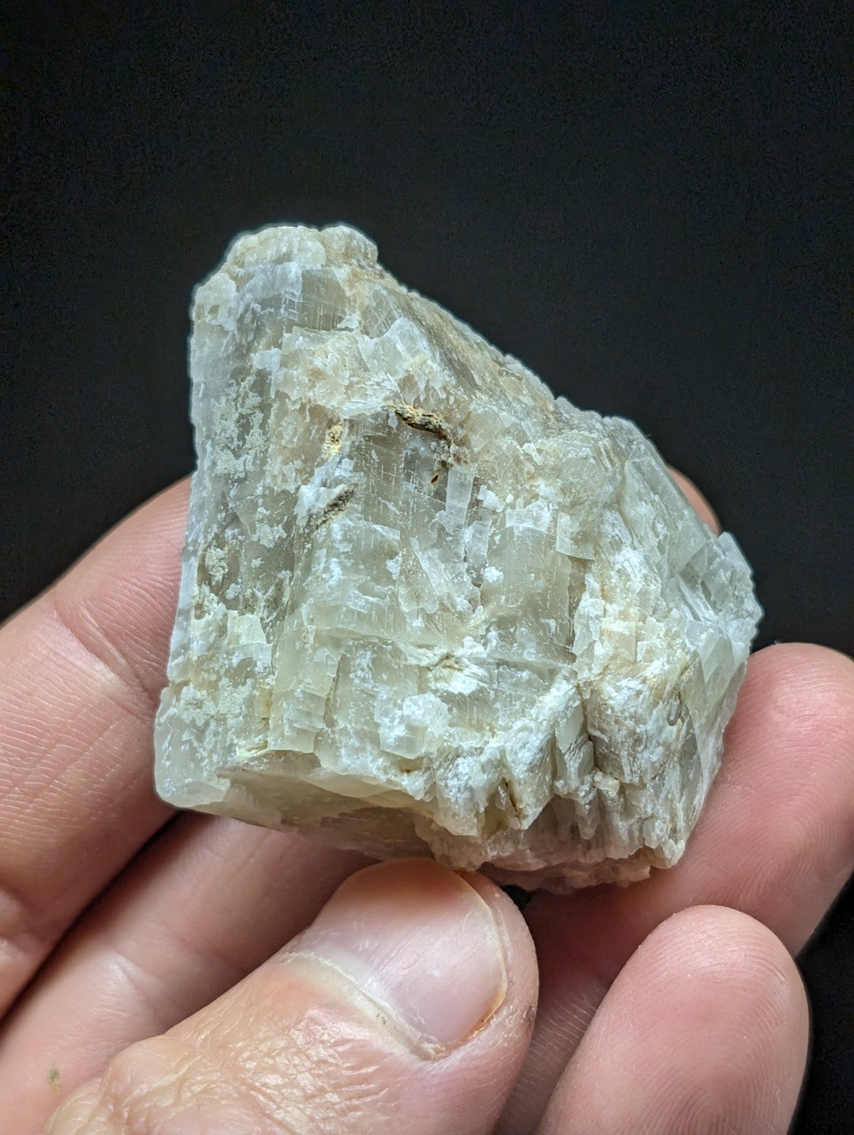 A translucent, pale greenish-white mineral specimen with a crystalline structure and rough, jagged edges.