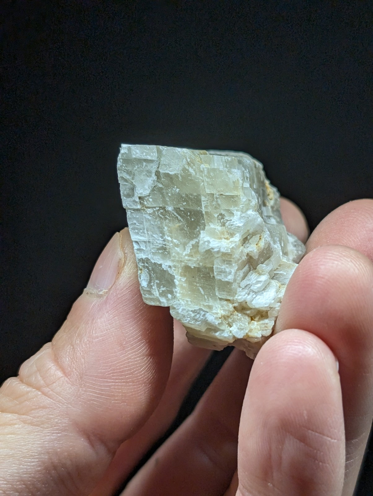 A translucent, pale greenish-white mineral specimen with a crystalline structure and visible internal striations.