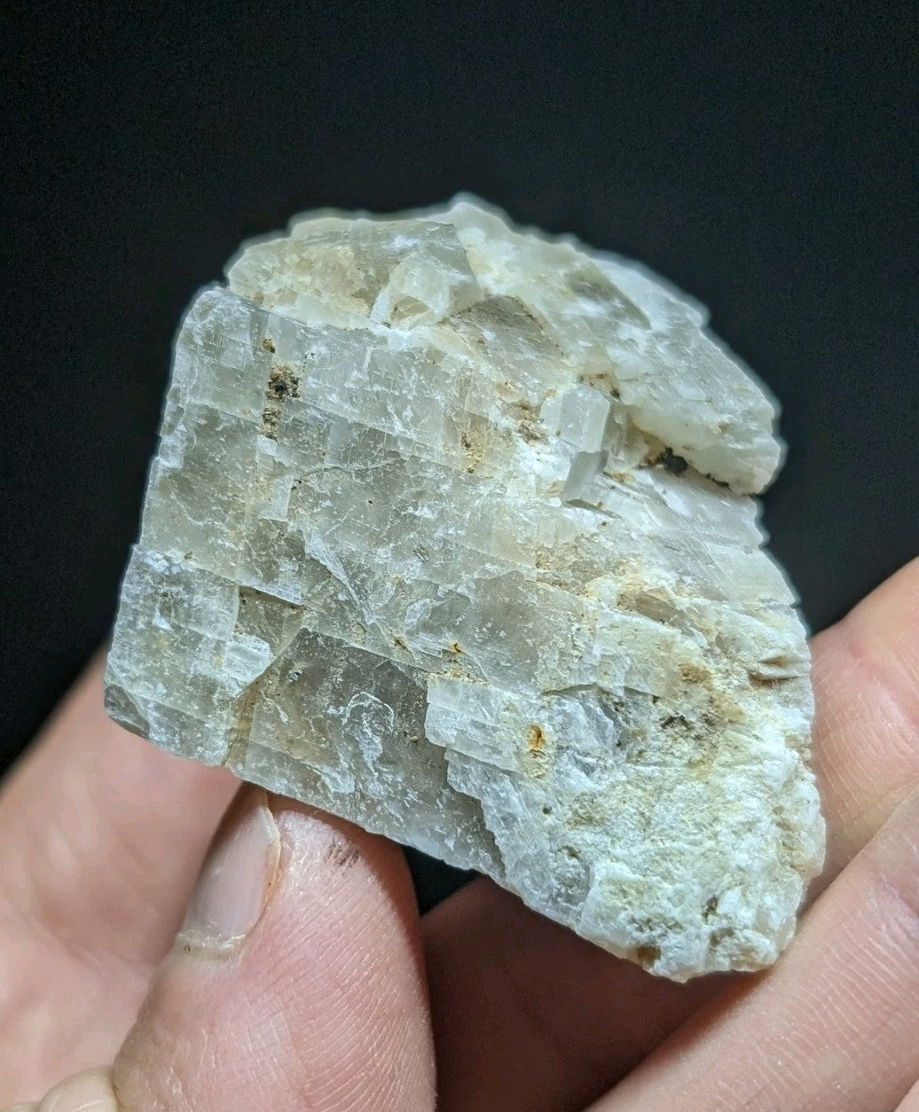A translucent, pale gray mineral specimen with distinct crystalline layers and subtle brownish inclusions.