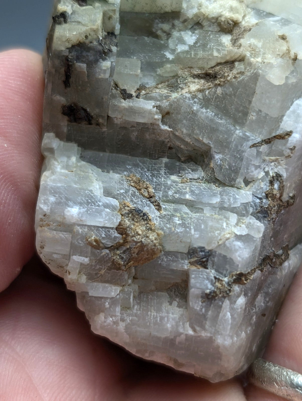 A translucent pale gray calcio carbonatite mineral with crystalline facets and dark inclusions from Magnet Cove Arkansas