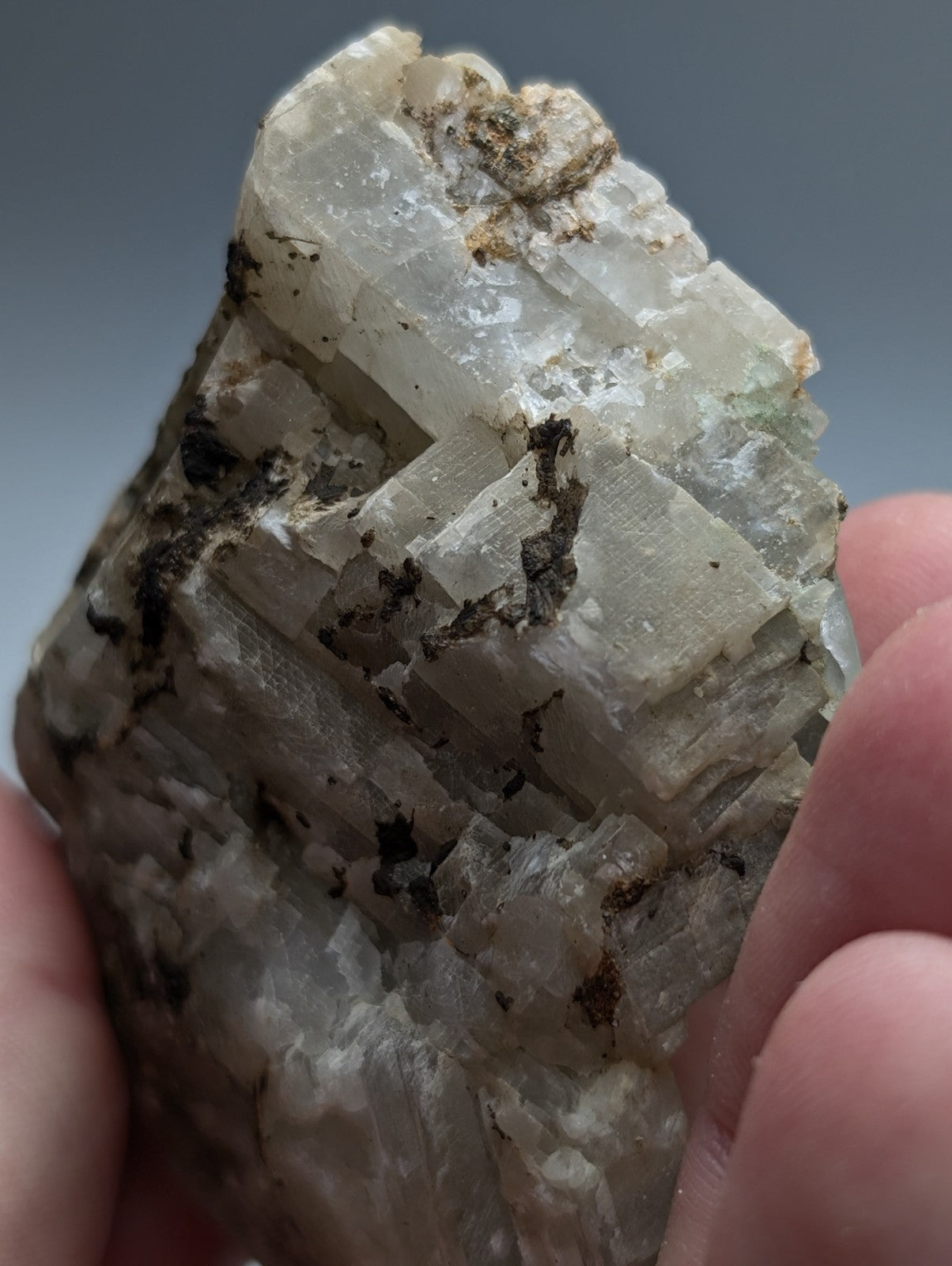 A translucent pale greenish-white calcio carbonatite mineral with dark brown inclusions from magnet cove arkansas