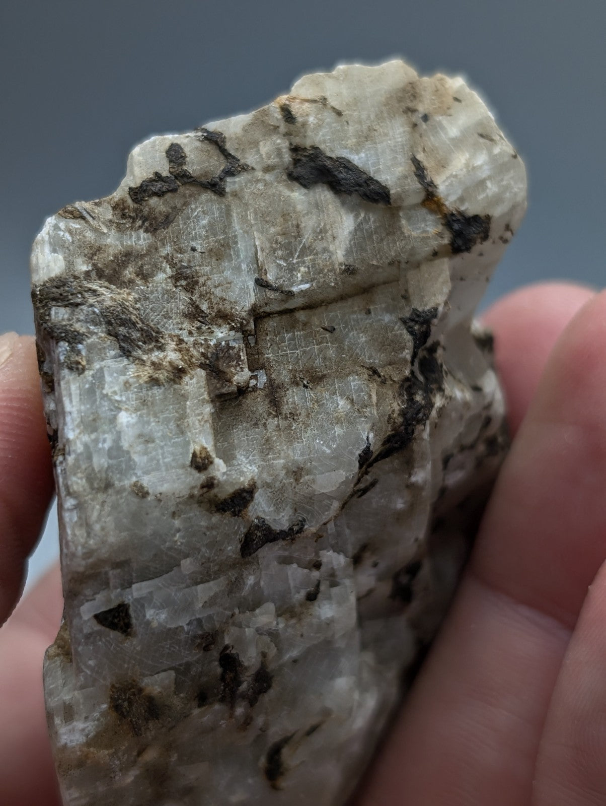 A rough translucent white calcio carbonatite mineral with dark inclusions and crystalline facets from magnet cove arkansas