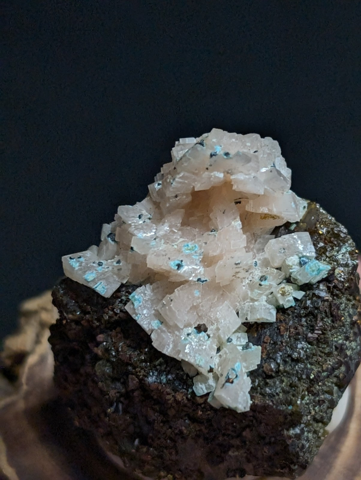 A translucent, pale pink mineral specimen with crystalline formations and scattered turquoise inclusions.