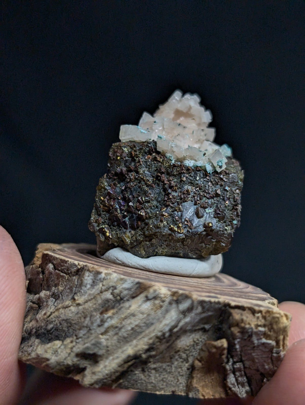 A mineral specimen featuring a cluster of translucent, pale pink and white crystals growing from a dark, rough-textured rock base.