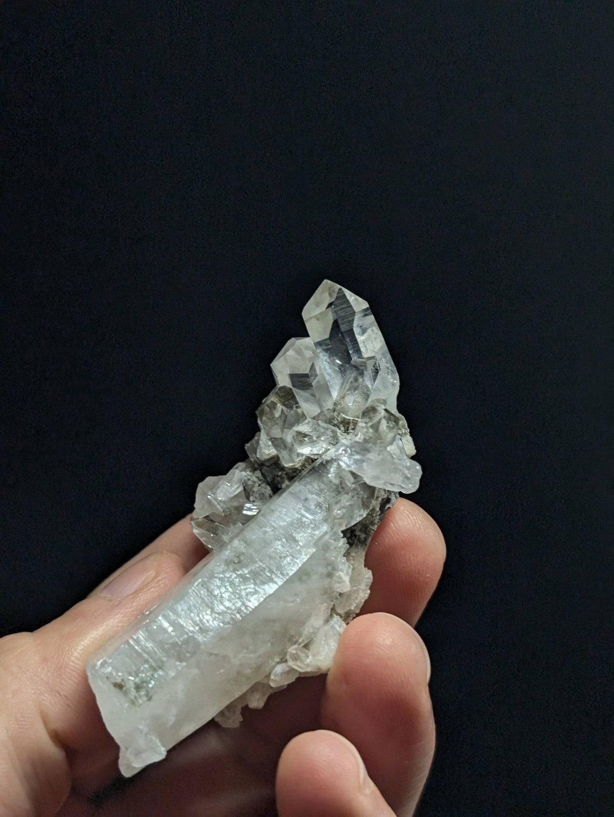 A translucent, clear quartz crystal cluster with sharp facets and a natural, rugged base.