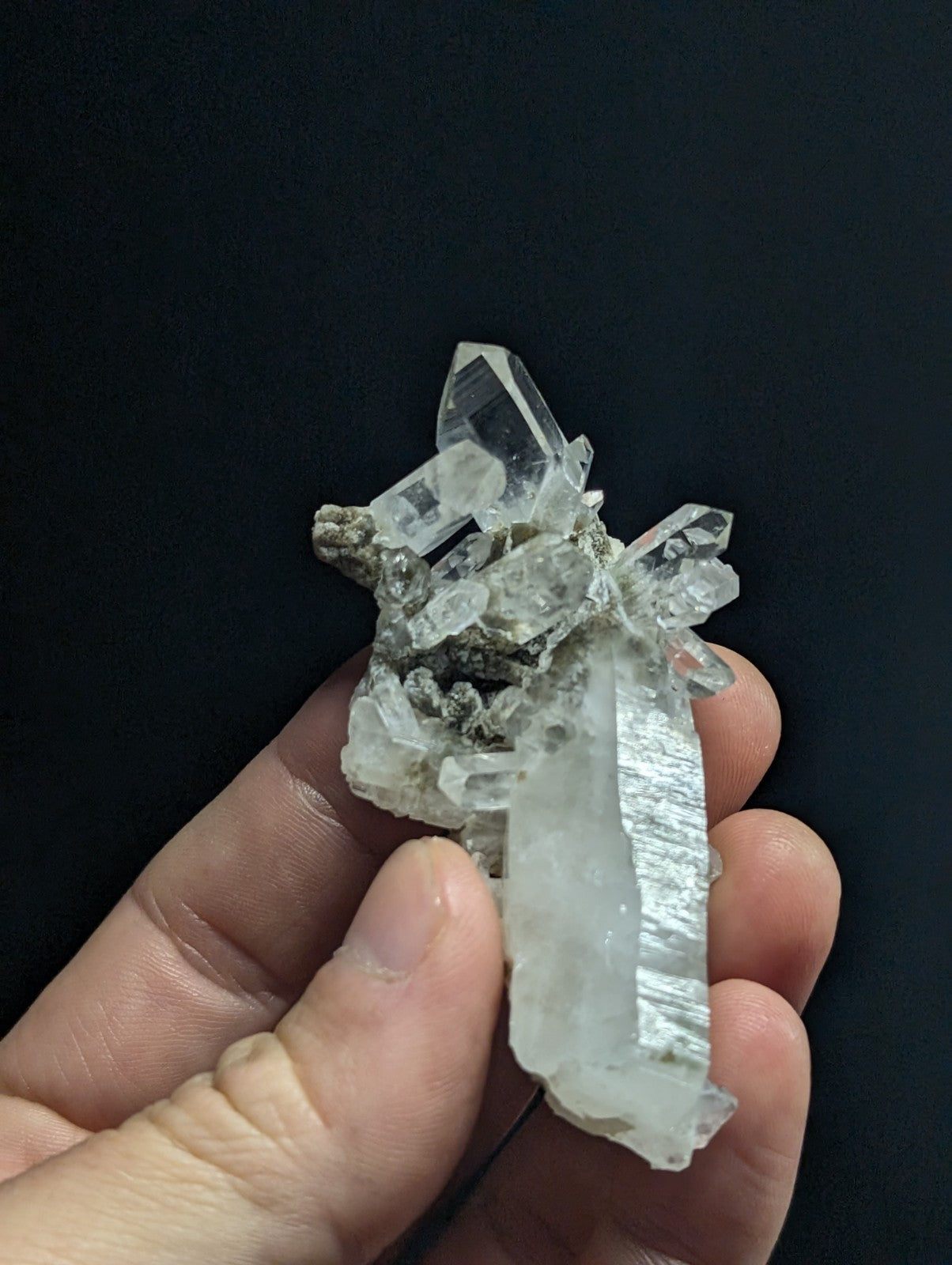 A translucent quartz crystal cluster with clear, faceted points and a rougher gray matrix base.