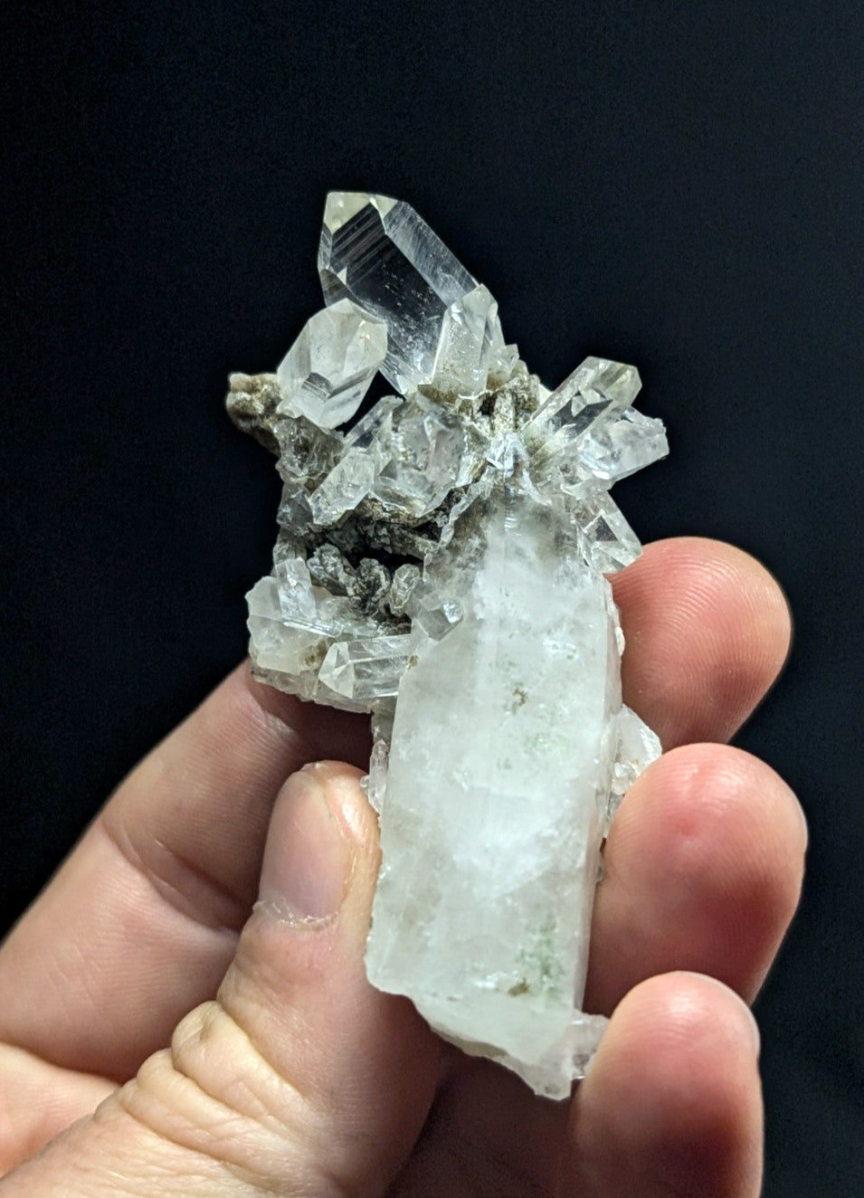 A translucent quartz crystal cluster with clear, faceted points and a rougher matrix base.