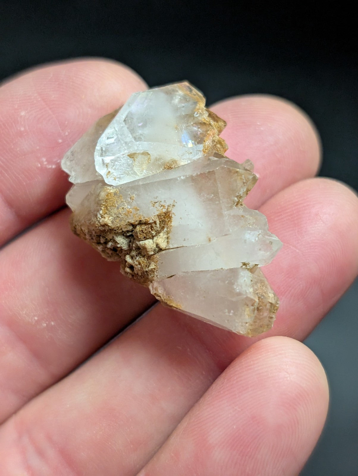 A cluster of translucent quartz crystals with a natural, earthy brown matrix holding them together.