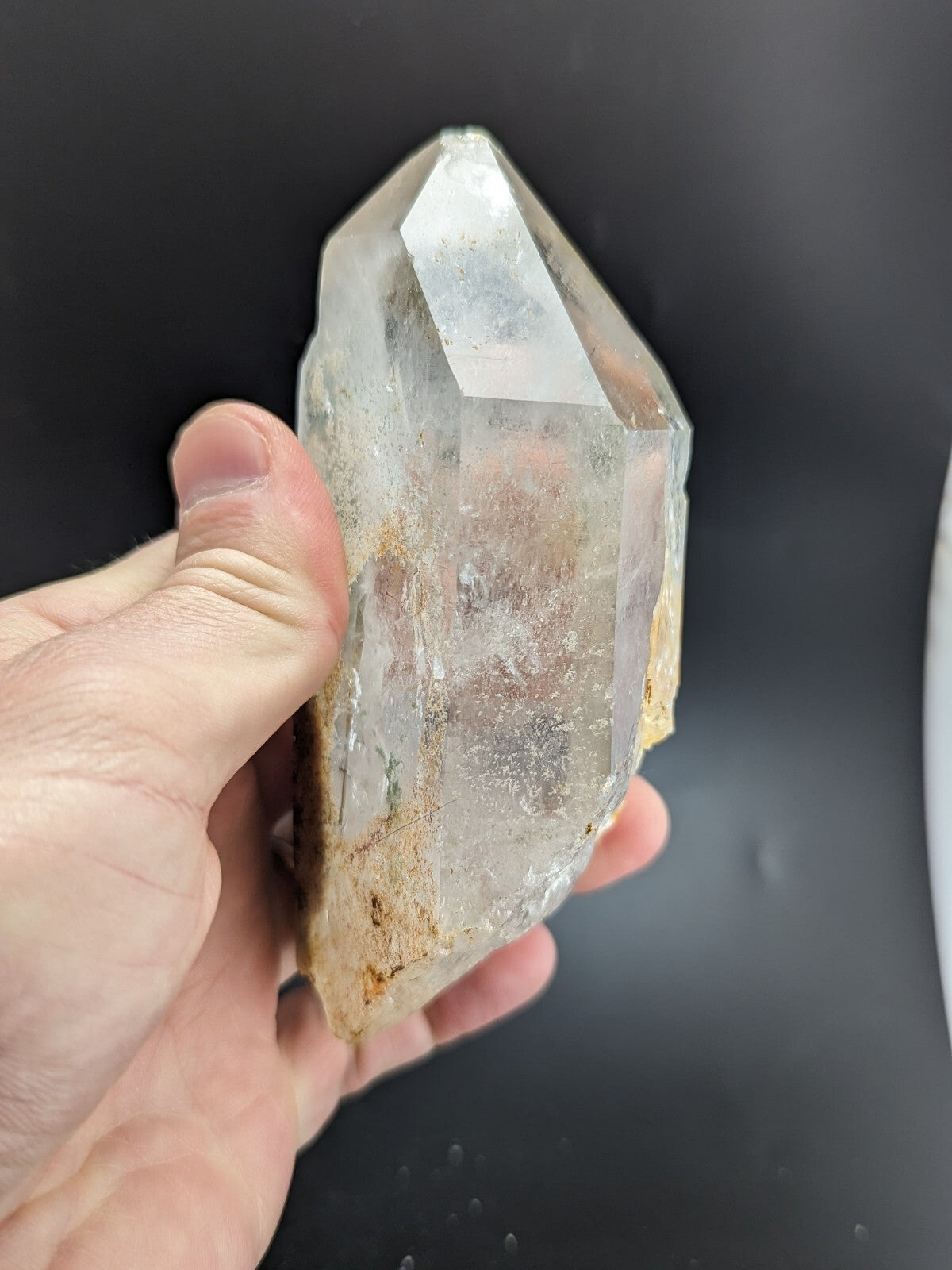 A clear, faceted quartz crystal with natural inclusions and a golden-brown base.