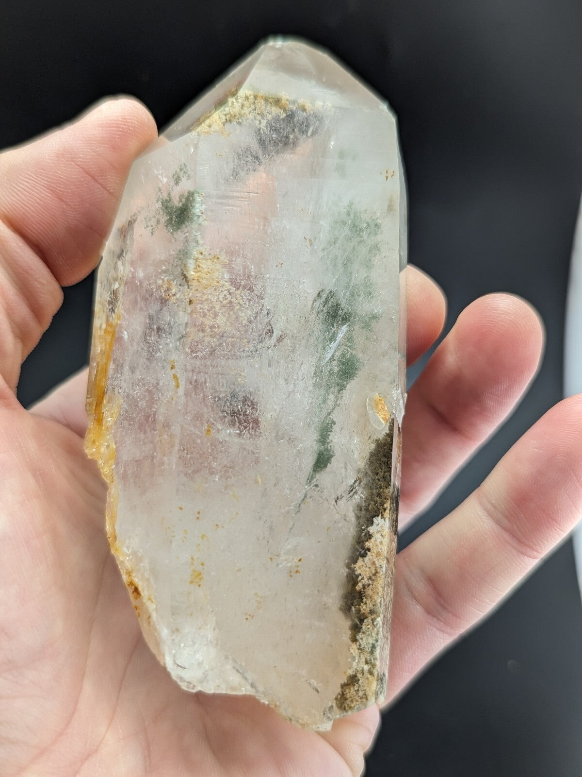 A translucent, clear quartz crystal with natural green and yellow inclusions.