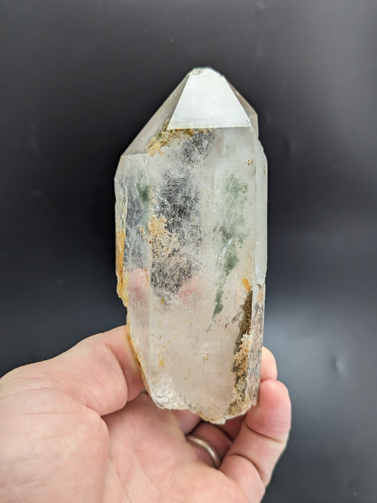 A translucent, clear quartz crystal with natural inclusions and a pointed tip.