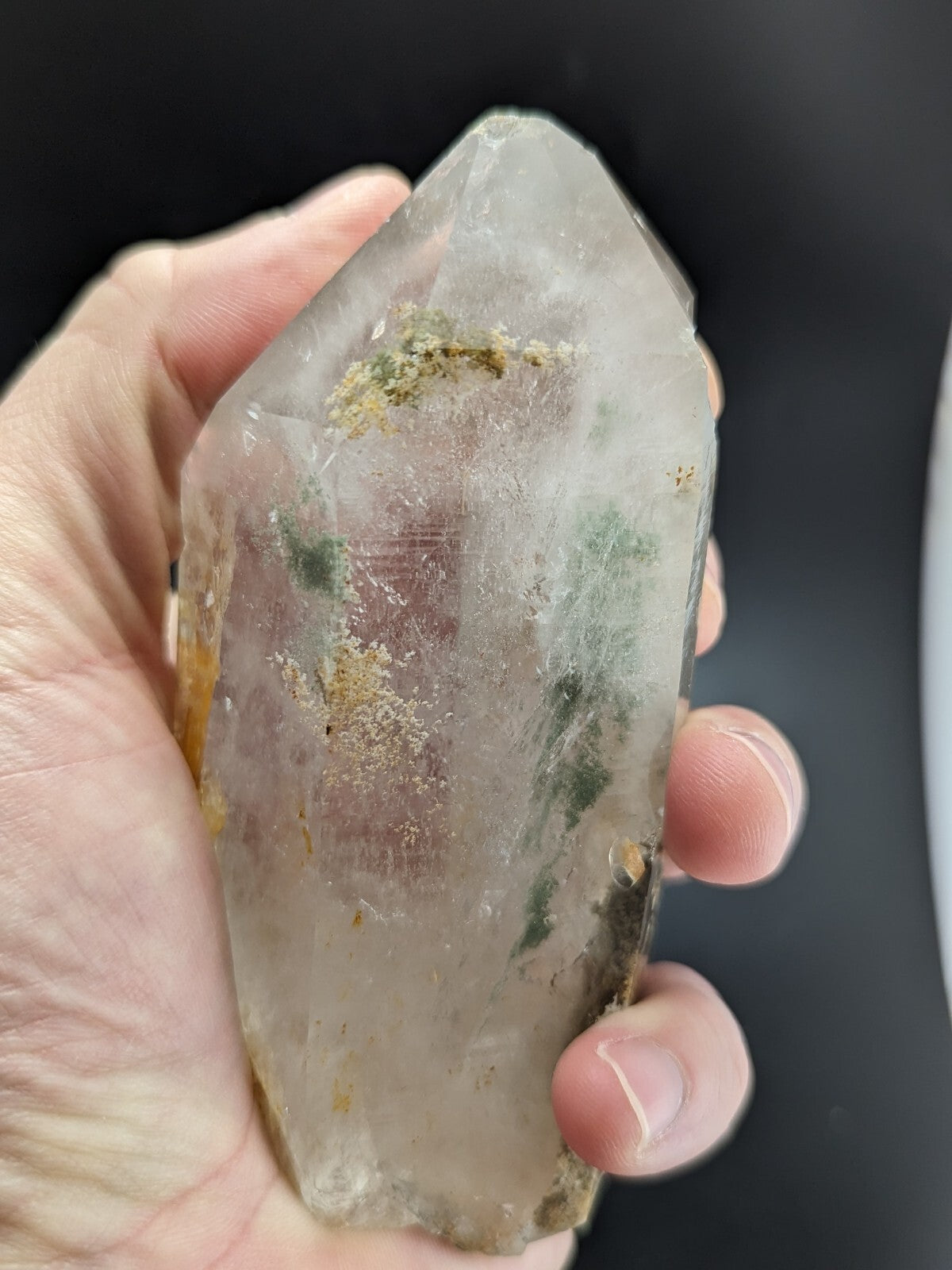 A translucent, clear quartz crystal with natural green and yellow inclusions.