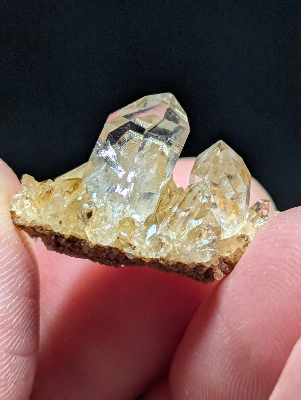A translucent yellowish quartz crystal cluster with sharp, faceted points and a rough brown base.