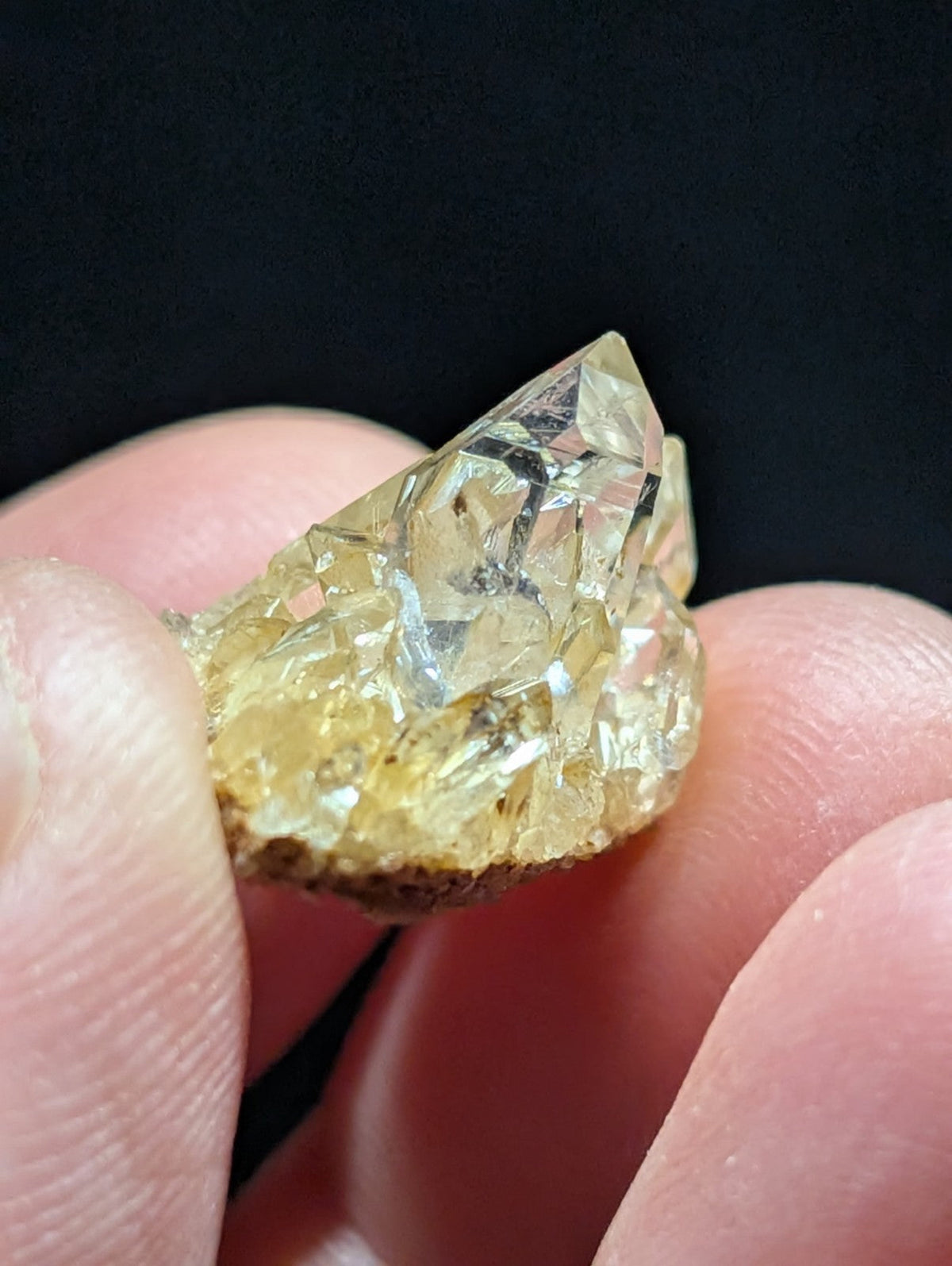 A translucent yellow crystal cluster with sharp, faceted points and a rough, earthy base.
