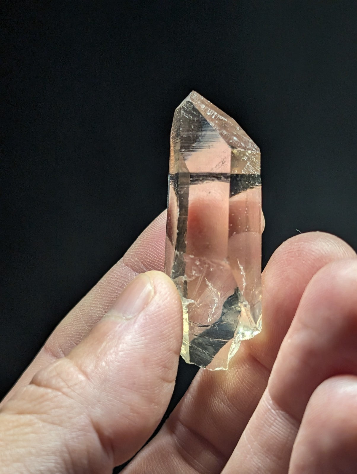 A translucent, pale yellow quartz crystal with a pointed tip and natural facets.