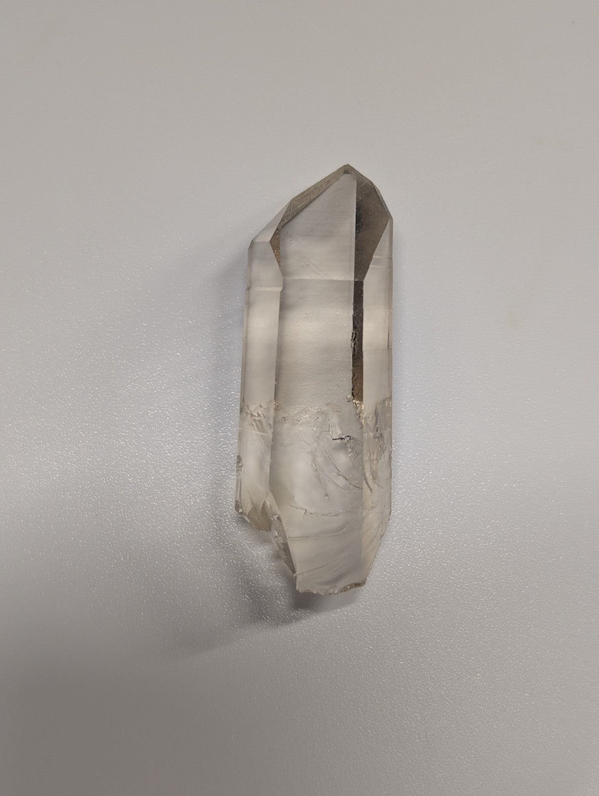 A translucent, smoky quartz crystal with a pointed tip and natural striations.