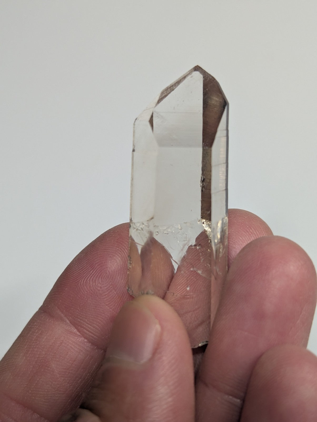A clear, transparent quartz crystal with a pointed tip and natural facets.