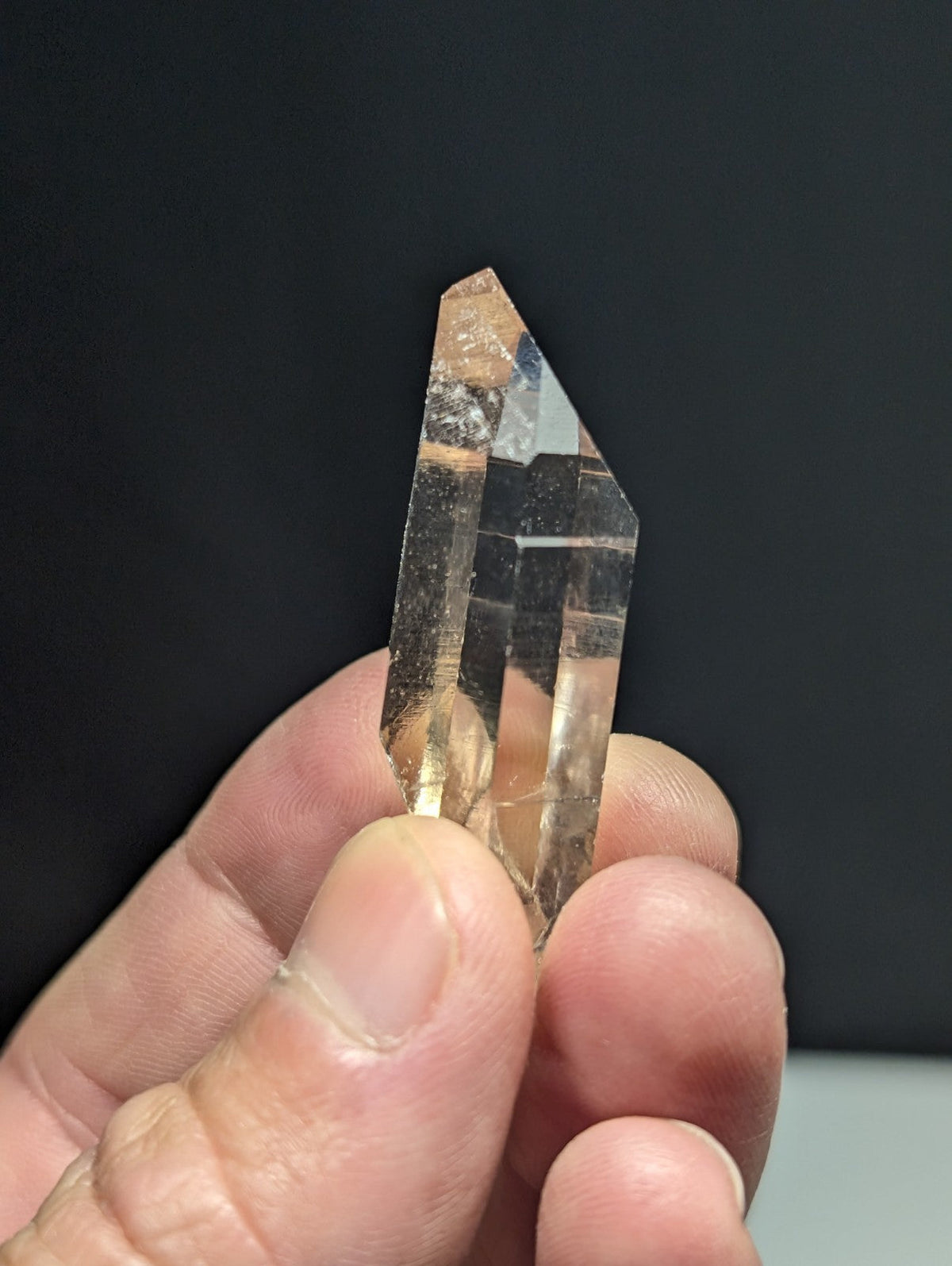 A translucent, clear quartz crystal with a pointed tip and visible internal striations.