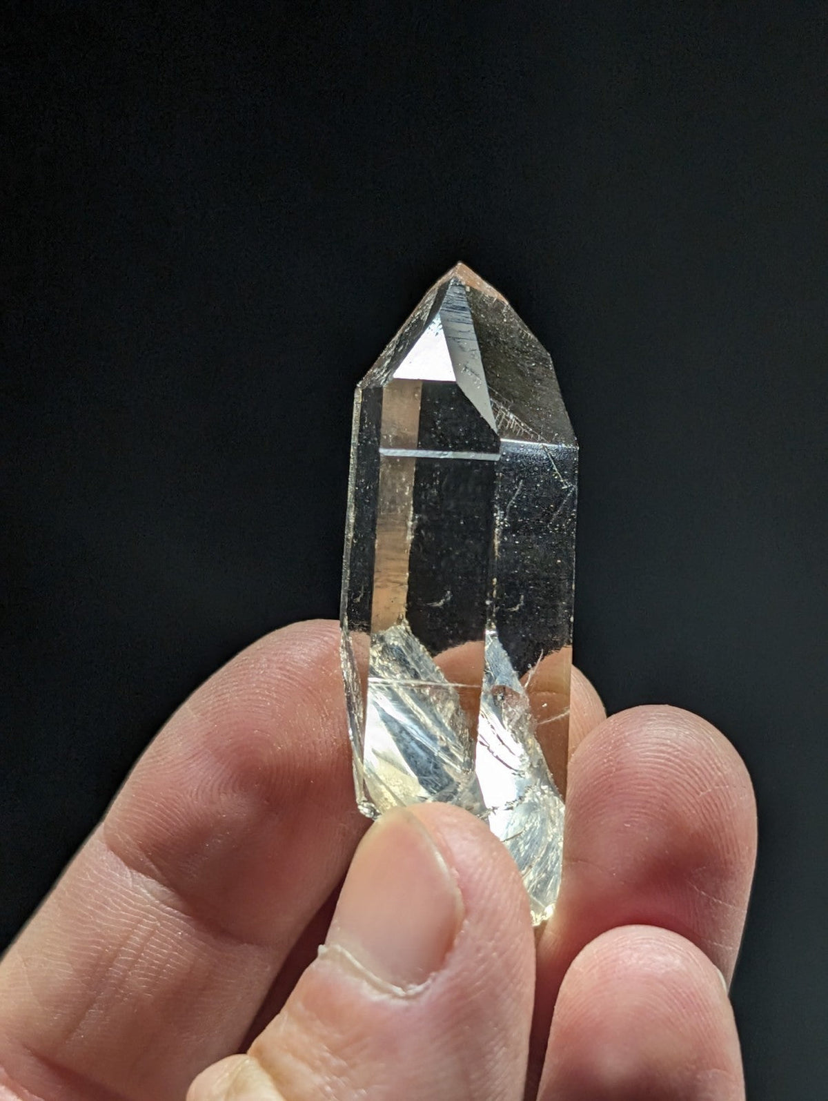 A clear, faceted quartz crystal held in a hand.