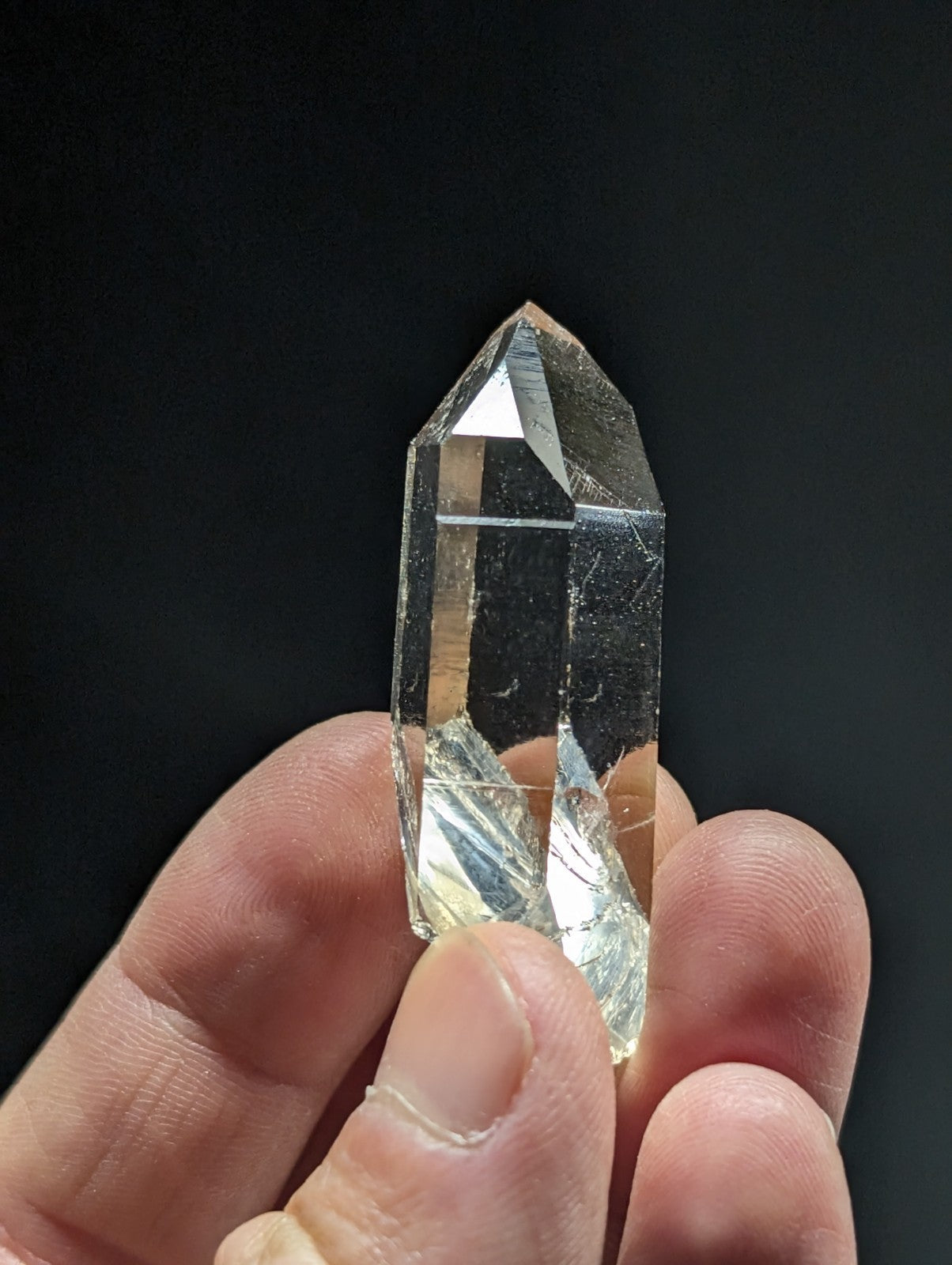 A clear, faceted quartz crystal held in a hand.
