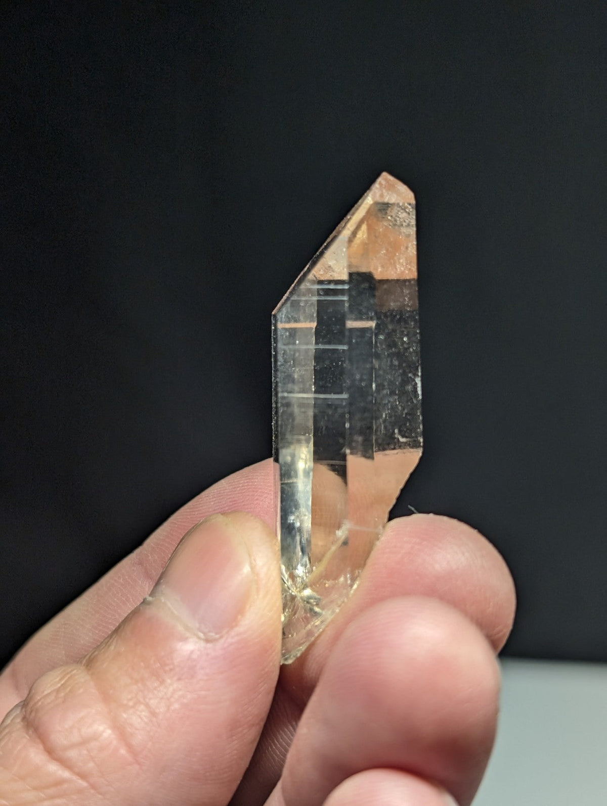 A translucent, clear quartz crystal with a pointed tip and visible internal striations.