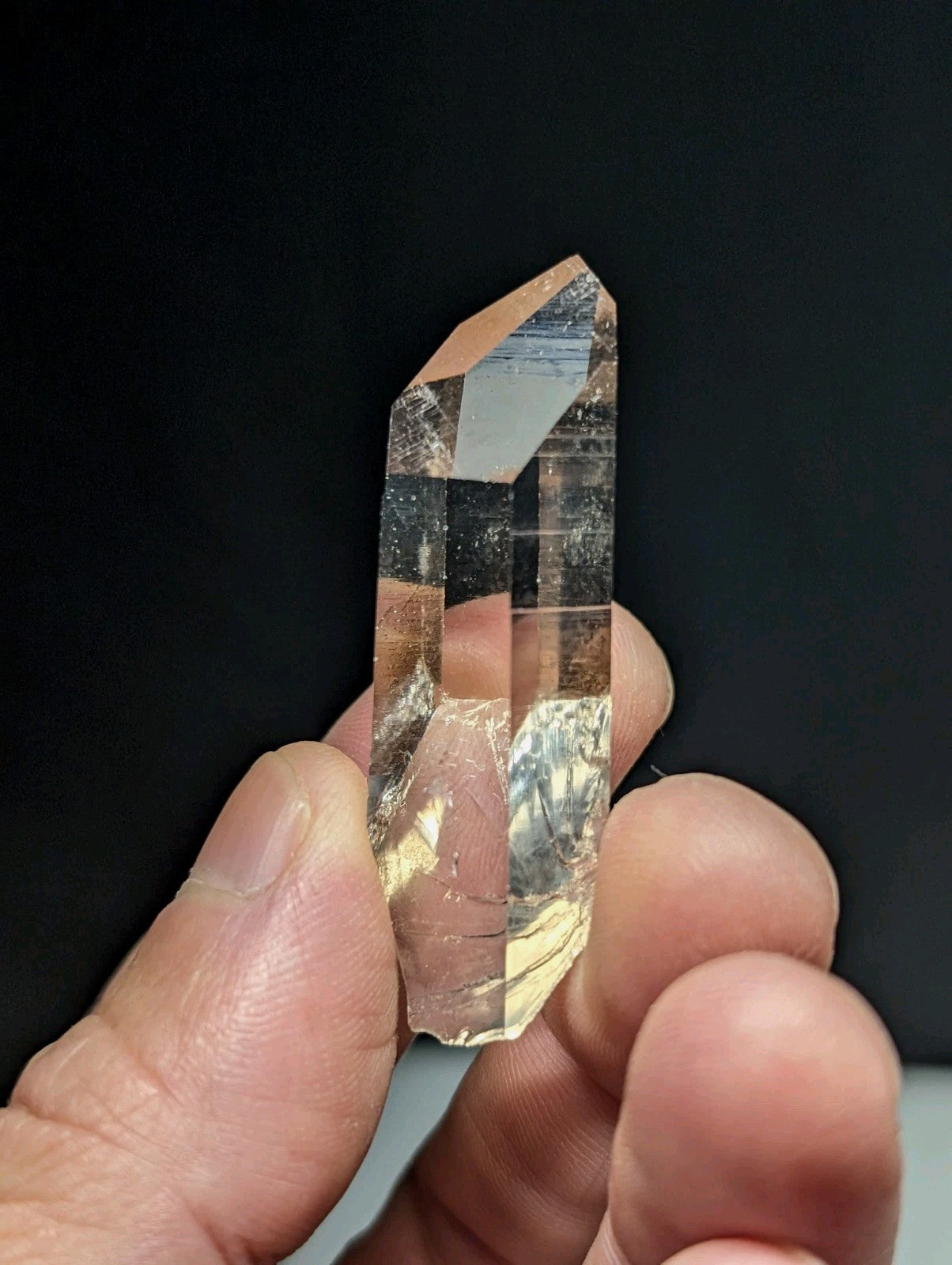 A translucent, clear quartz crystal with a pointed tip and natural internal inclusions.