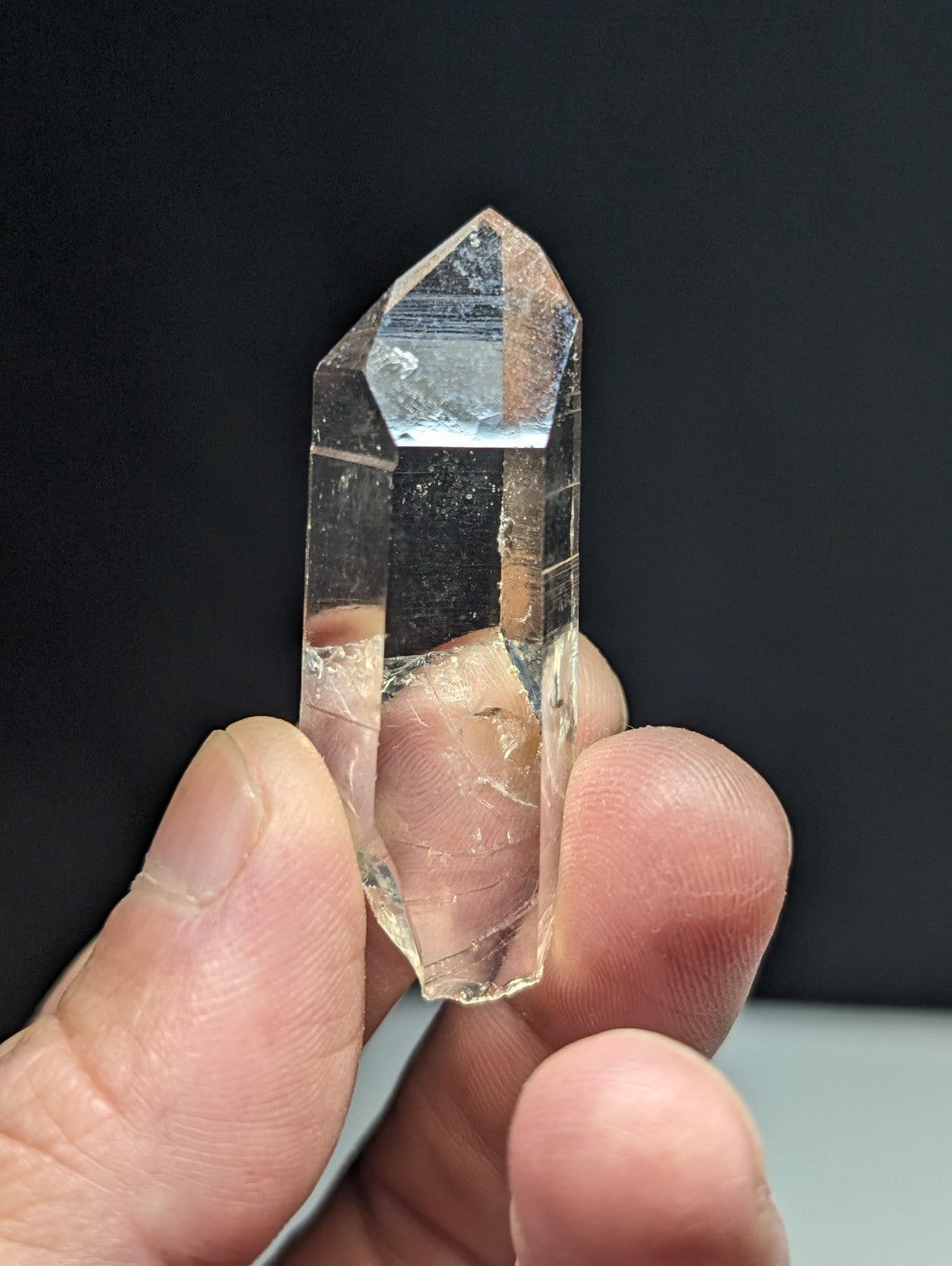A clear, transparent quartz crystal with a pointed tip and faceted sides.