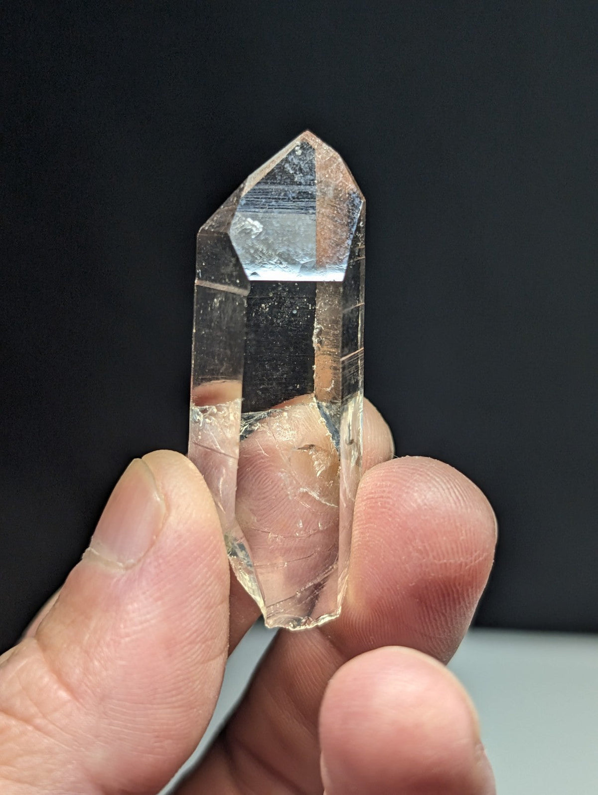 A clear, transparent quartz crystal with a pointed tip and faceted sides.