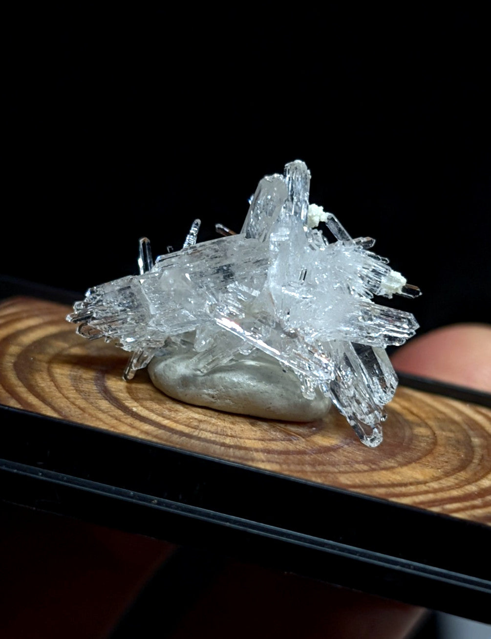 A clear, translucent quartz crystal cluster with sharp, jagged points and a natural, earthy base.