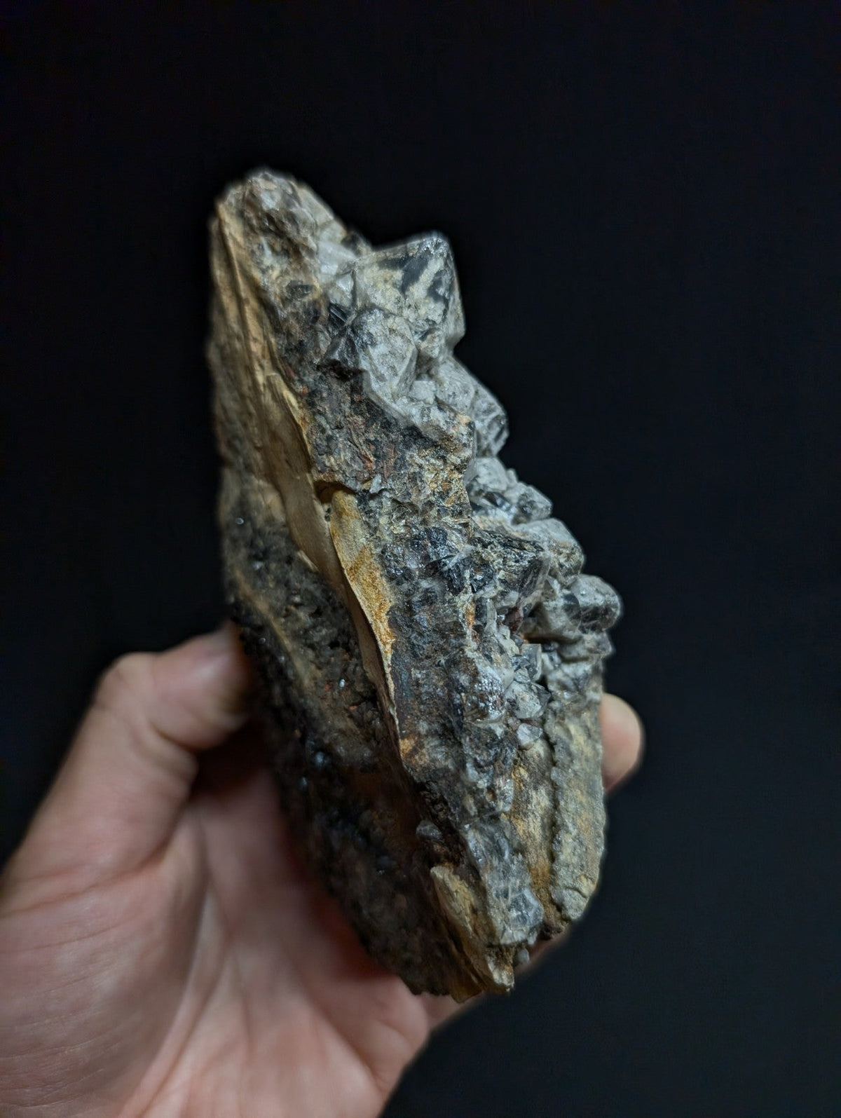 A rugged, irregularly shaped mineral specimen with a mix of gray and brown hues, featuring crystalline textures and natural fissures.