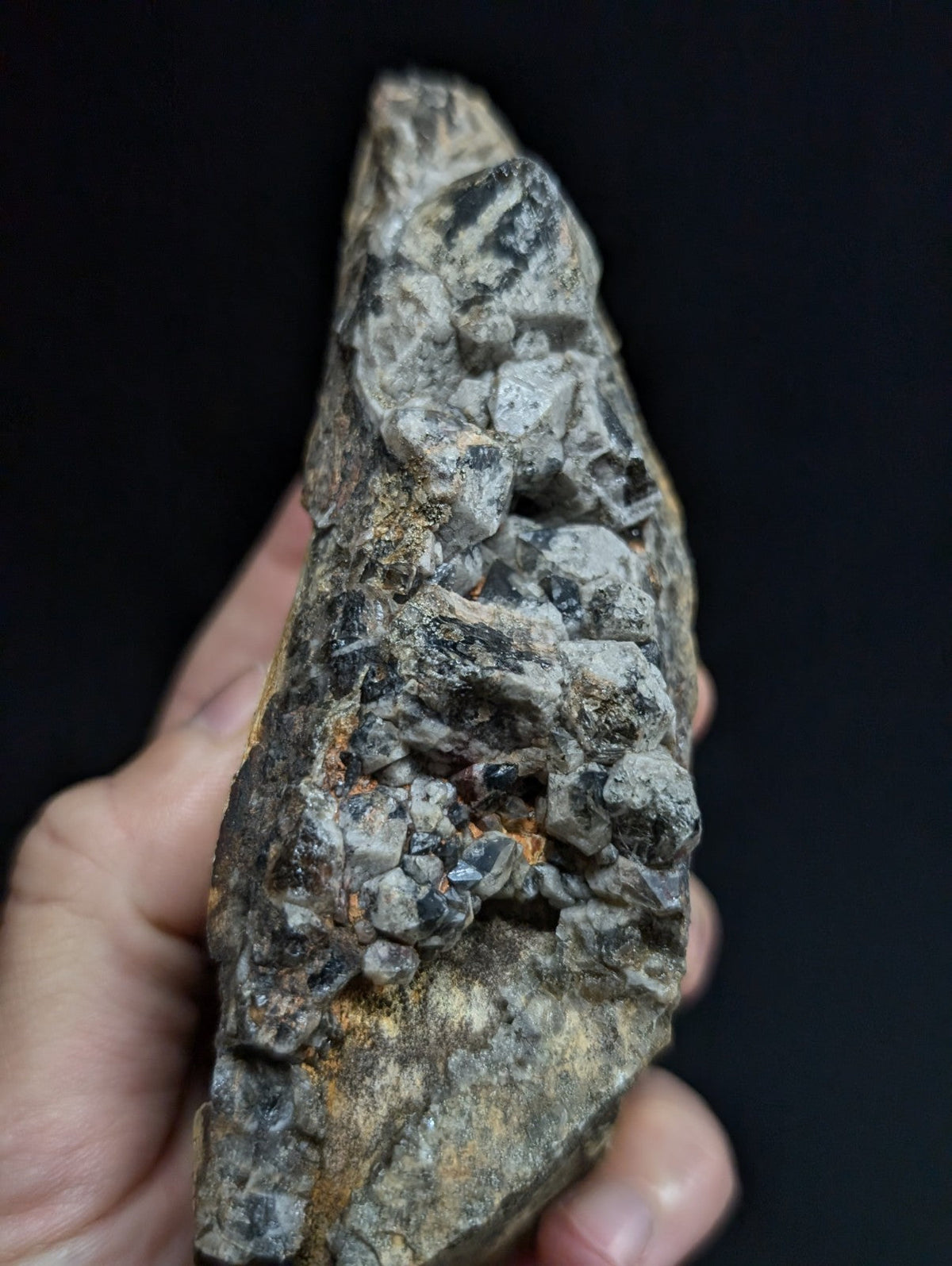 A rugged, irregularly shaped mineral specimen with a mix of dark gray and translucent crystalline formations embedded in a rougher matrix.