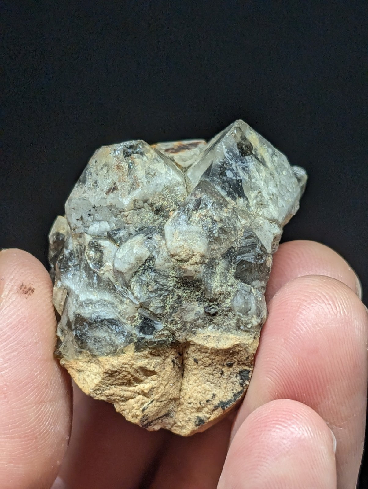 A rough, translucent greenish-gray mineral specimen with angular crystal facets and a yellowish base.
