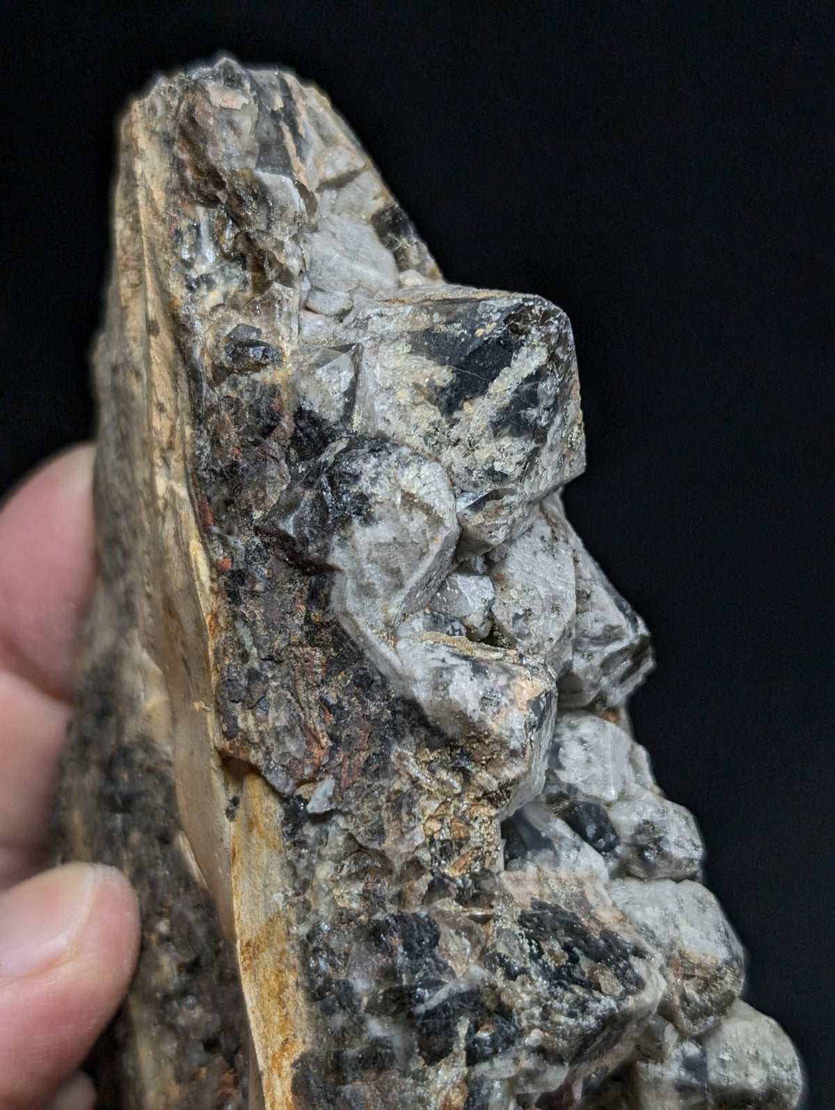 A rugged, grayish-black mineral specimen with crystalline formations and earthy matrix.