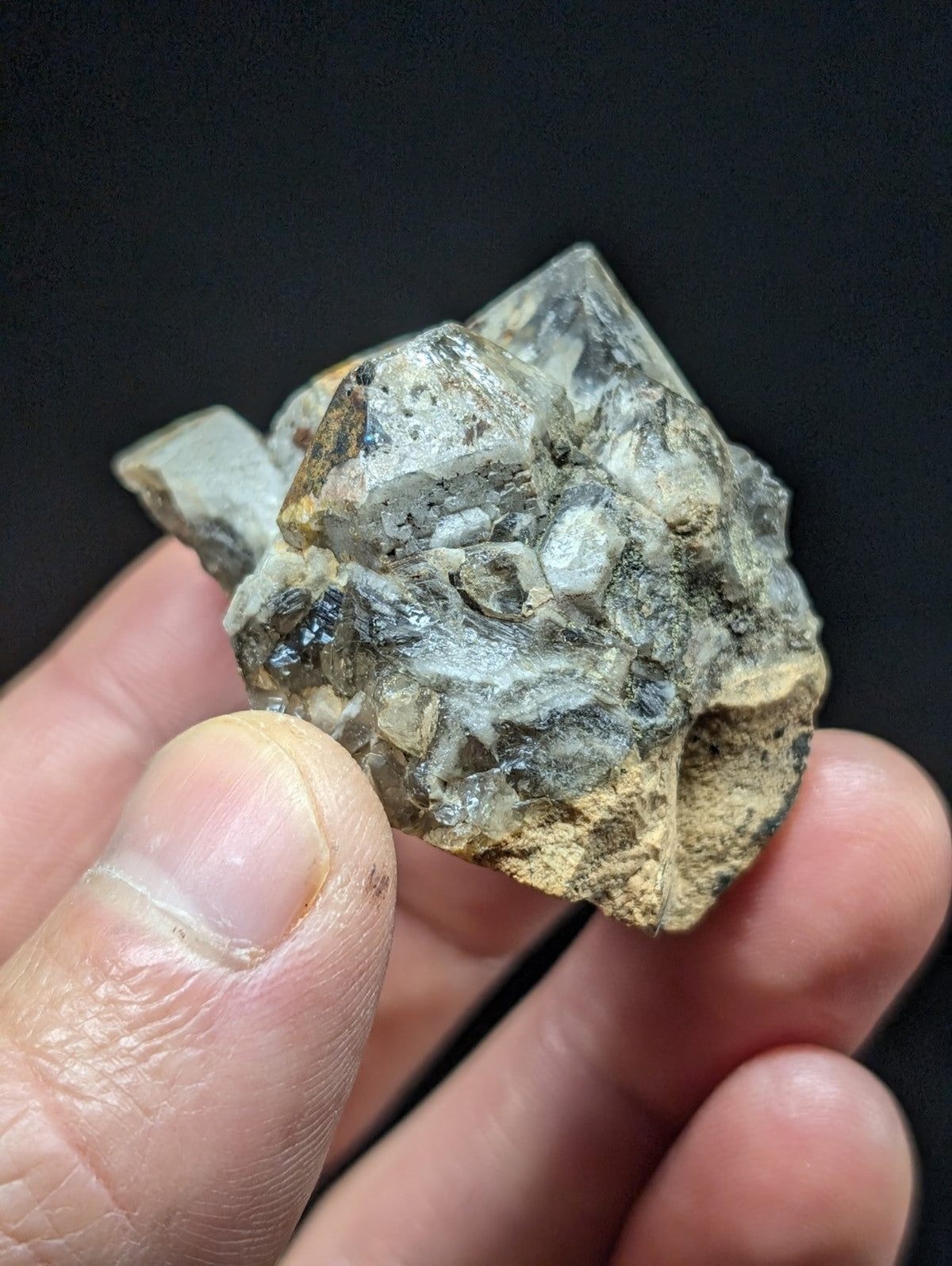 A rough, translucent quartz crystal cluster with a mix of clear and cloudy sections, accented by earthy brownish matrix material.