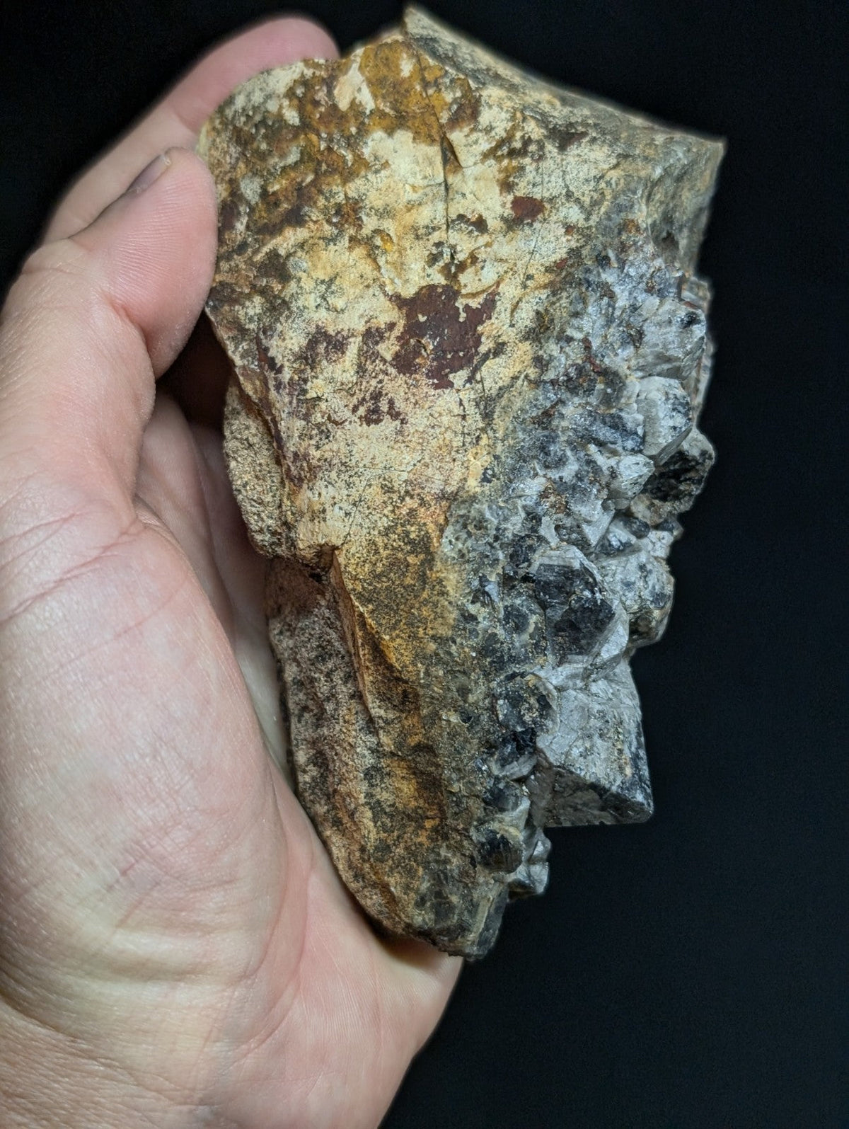 A rugged, irregularly shaped rock with a mottled surface of earthy browns, yellows, and grayish tones.