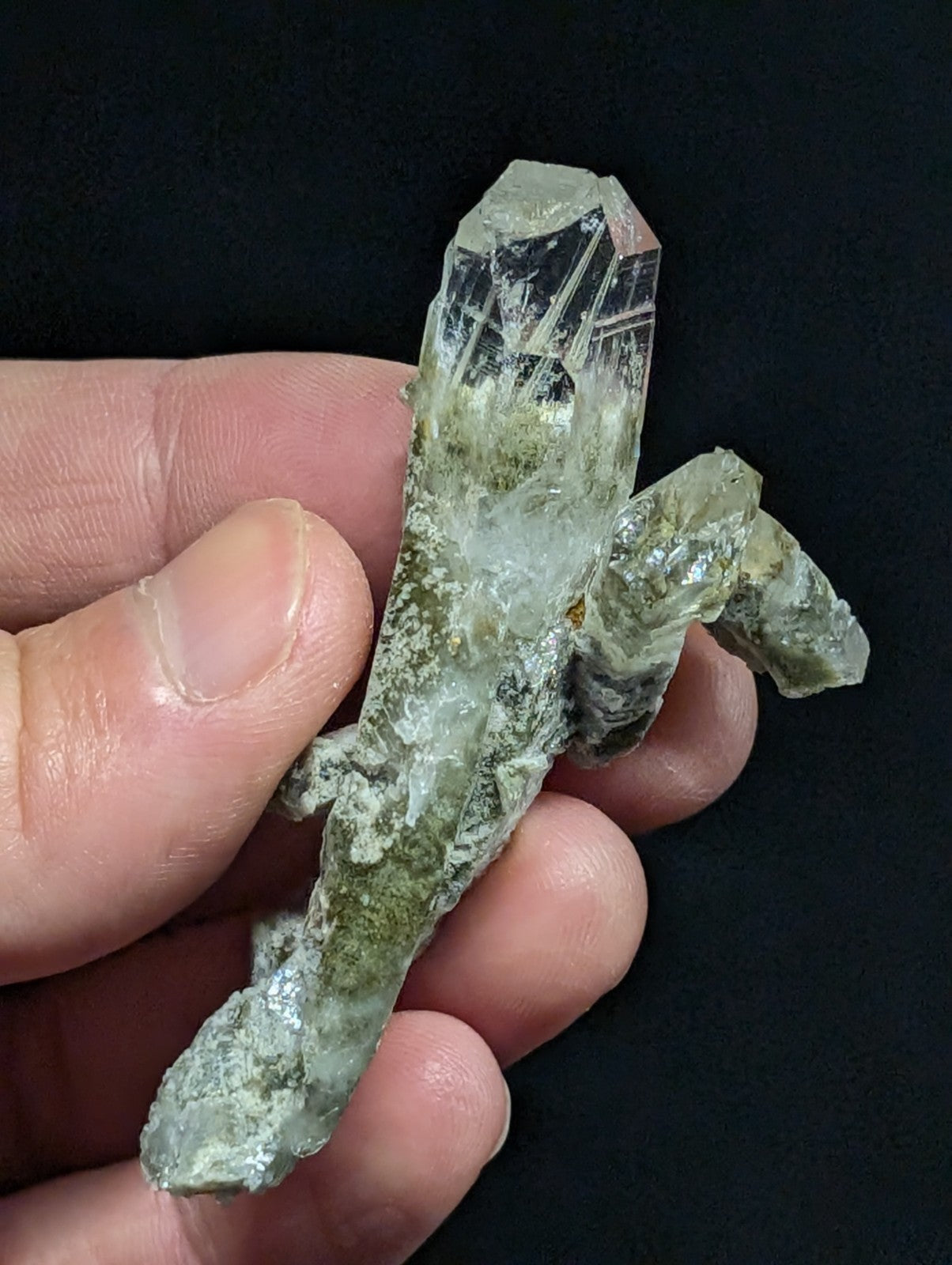 A translucent green quartz crystal cluster with a rough, earthy base and sharp, faceted points.