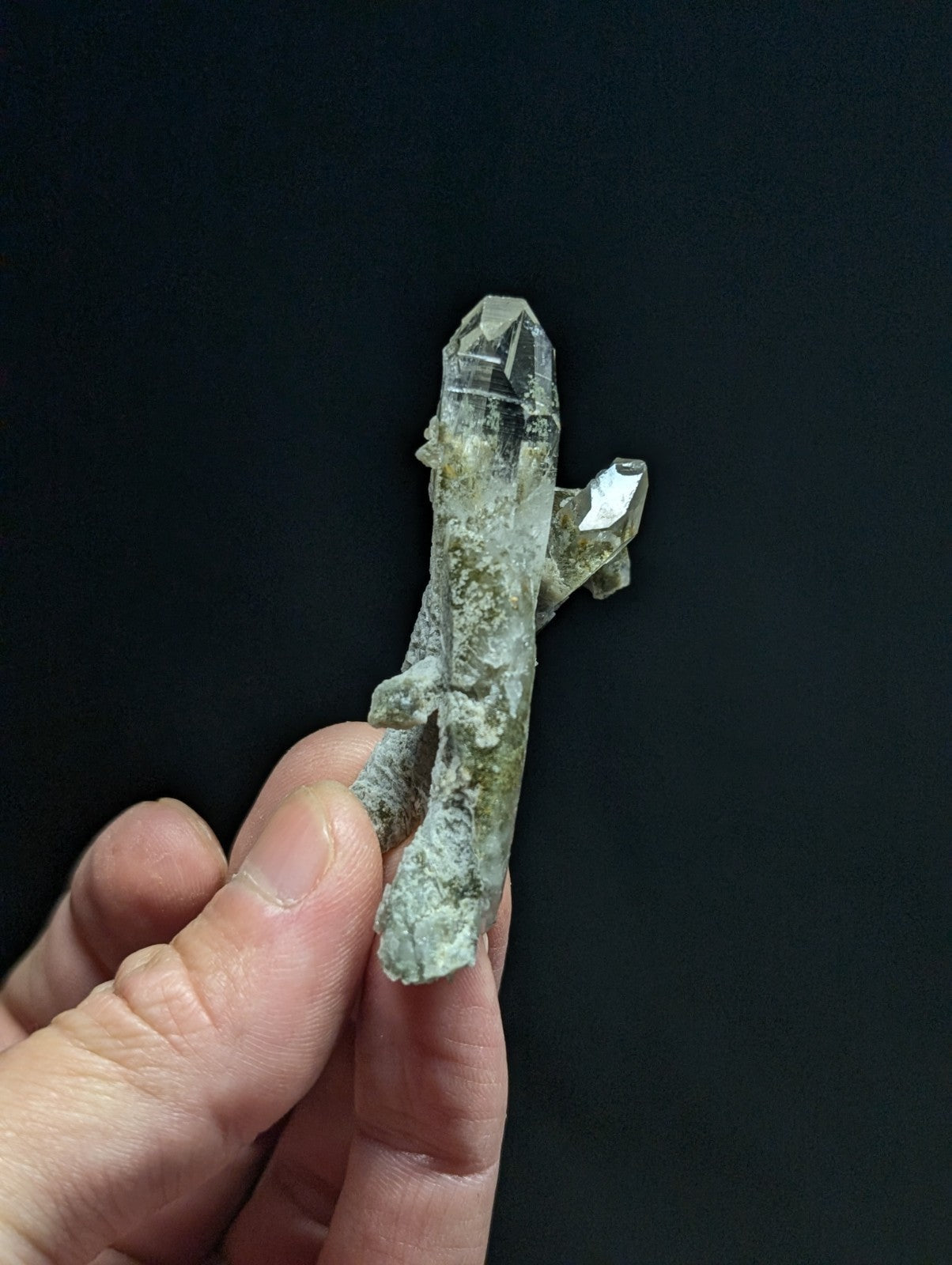 A translucent, pale green quartz crystal cluster with a pointed tip and natural mineral inclusions.