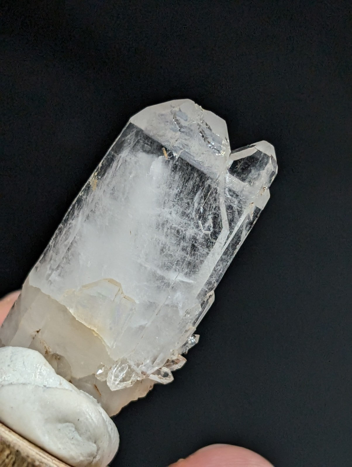 A translucent, clear quartz crystal with a pointed tip and natural facets.