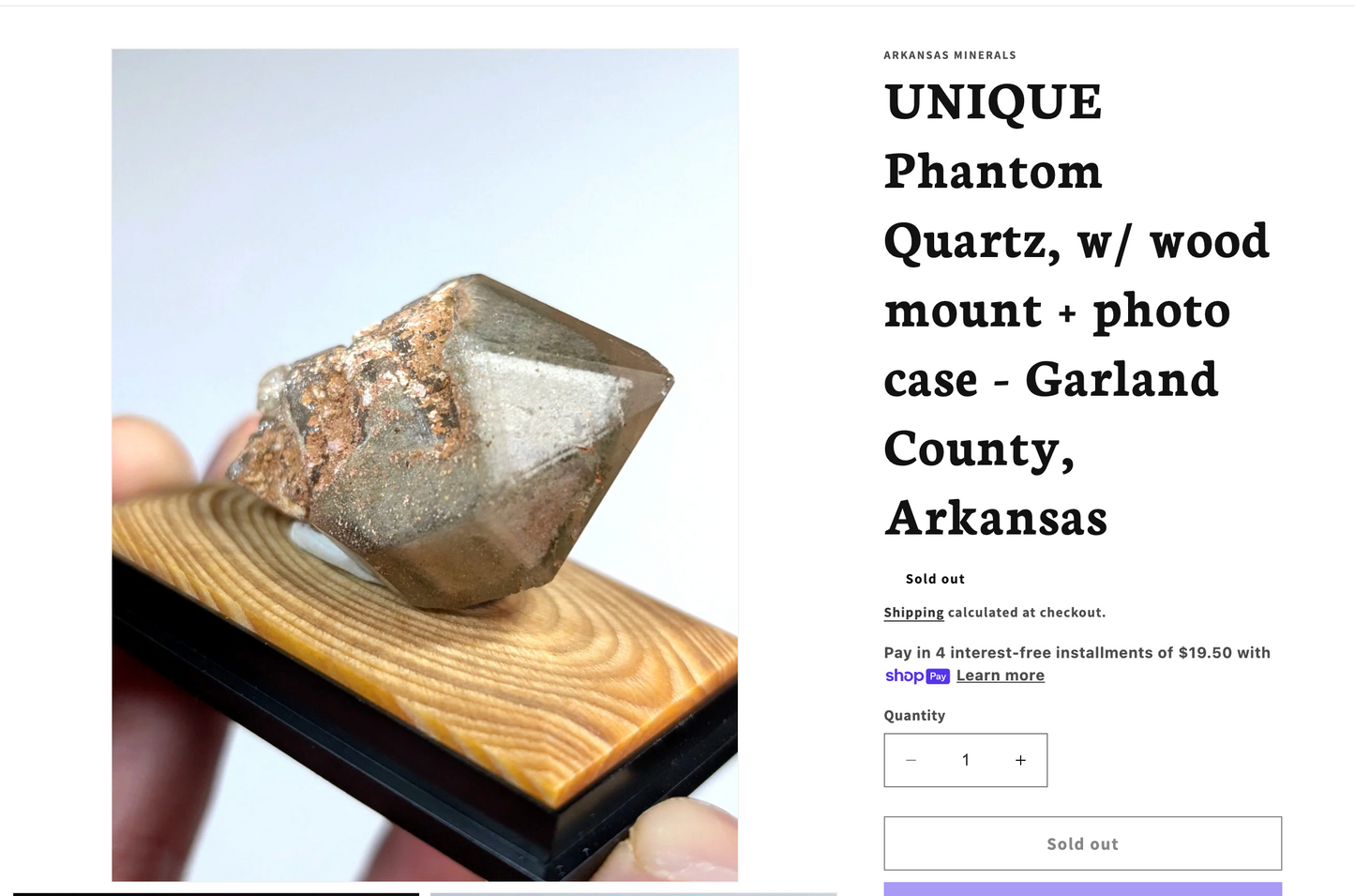 A translucent gray phantom quartz crystal with brownish mineral inclusions, mounted on a wooden base.