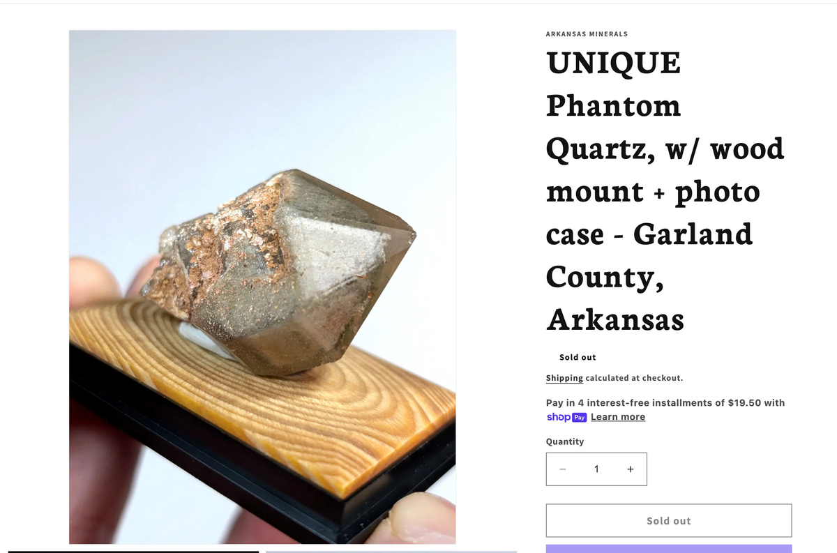 A translucent gray phantom quartz crystal with brownish mineral inclusions, mounted on a wooden base.