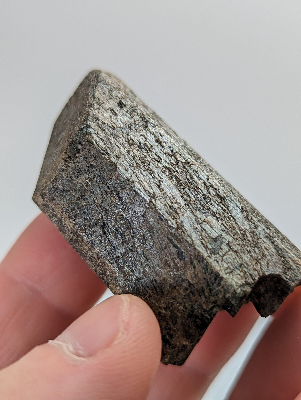 A rough, irregularly shaped piece of dark gray metallic ore with a textured surface and visible mineral veins.