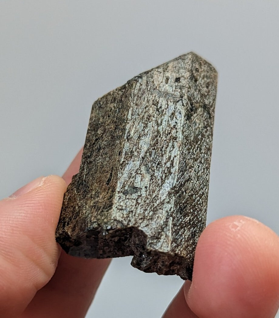 A dark, rough-textured mineral specimen with a metallic sheen and angular facets.
