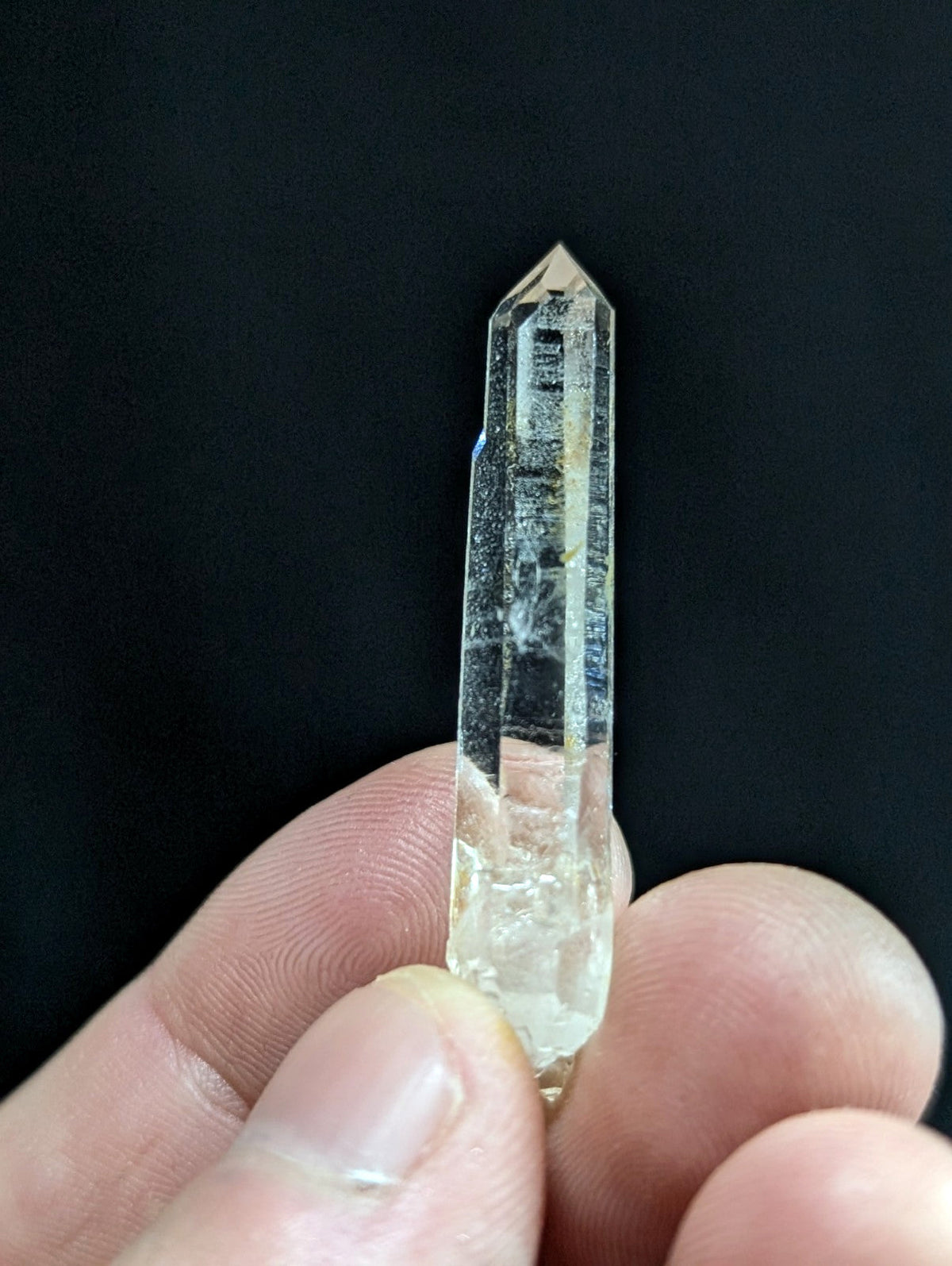 A clear, translucent quartz crystal with a pointed tip and visible internal inclusions.