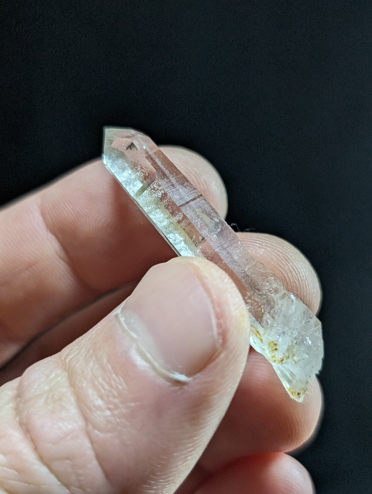 A translucent, clear quartz crystal with natural inclusions and a pointed tip.