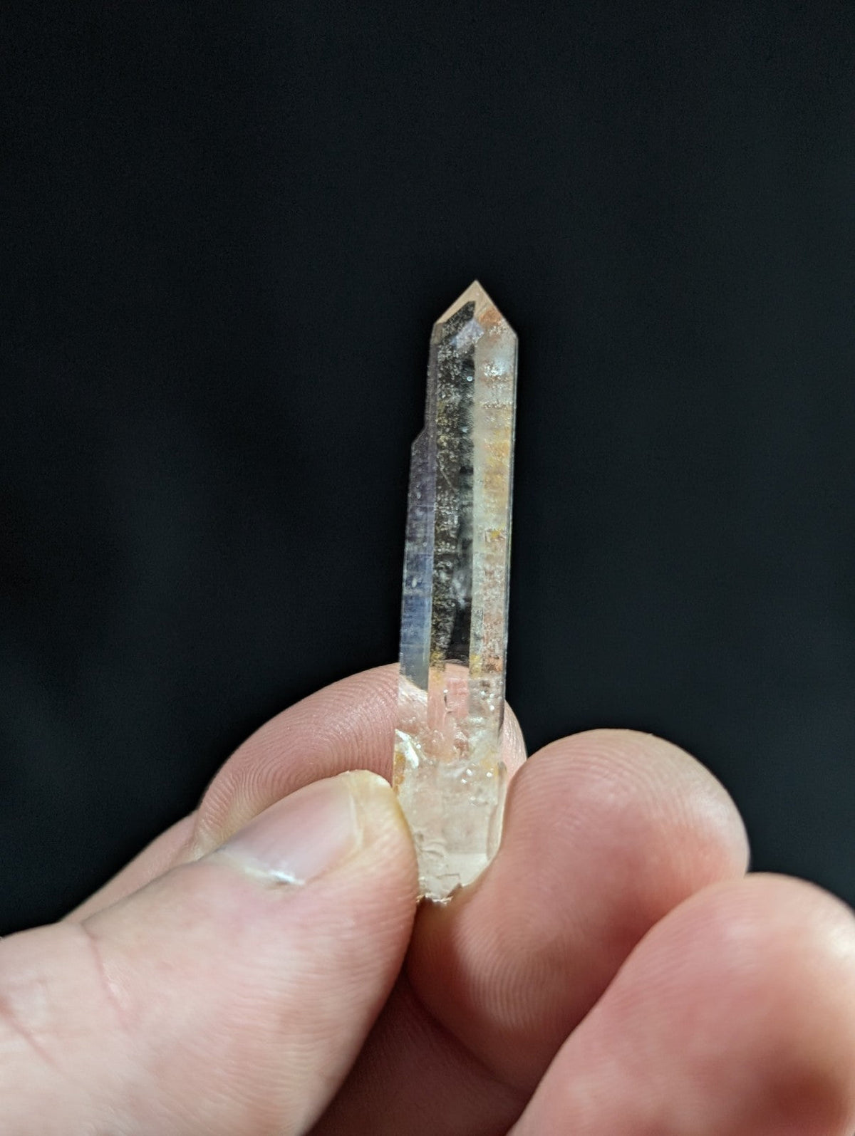 A translucent, clear quartz crystal with a pointed tip and visible internal inclusions.