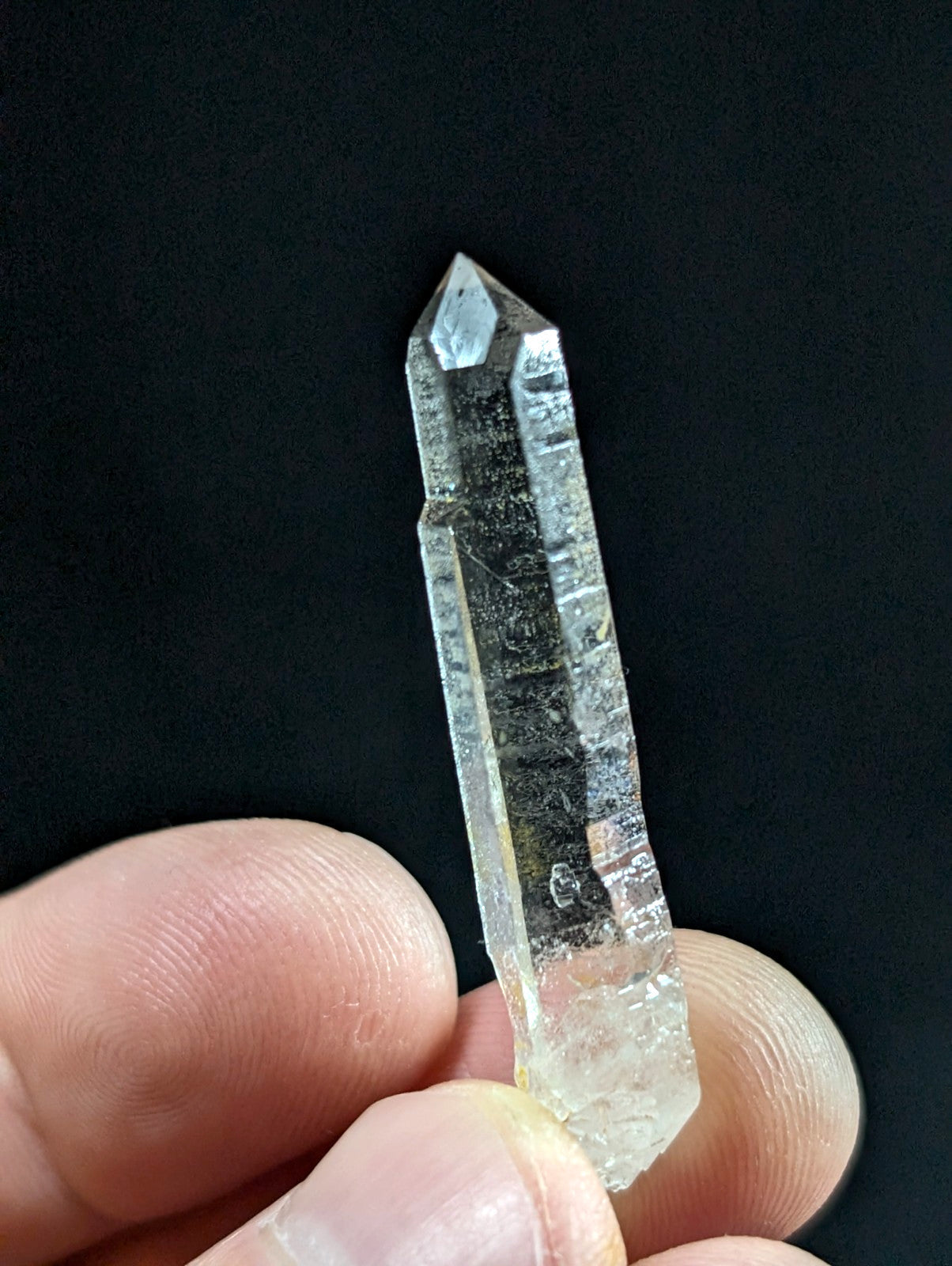 A clear, translucent quartz crystal with a pointed tip and visible internal inclusions.