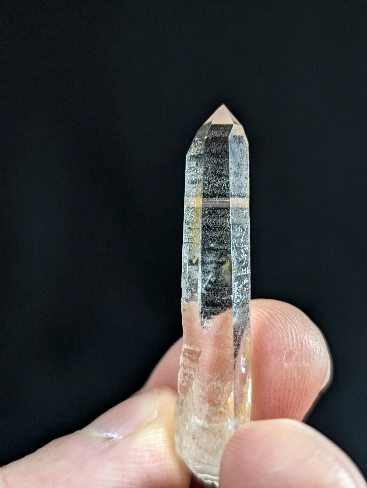 A translucent, clear quartz crystal with a pointed tip and natural internal striations.