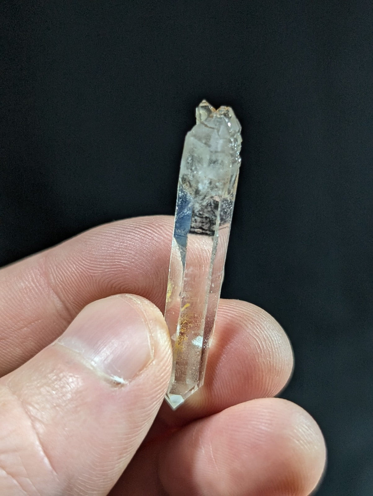 A translucent, clear quartz crystal with a pointed tip and natural inclusions.