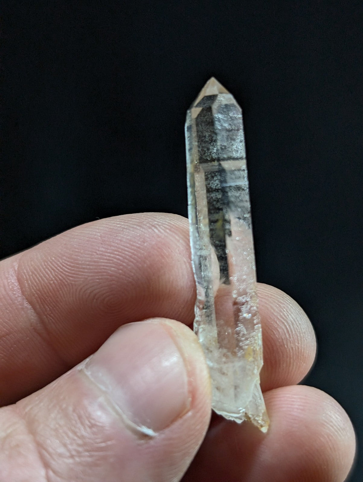 A translucent, clear quartz crystal with a pointed tip and natural internal inclusions.